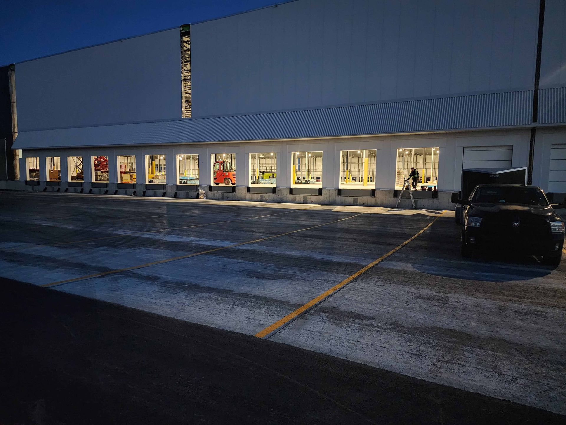 Une voiture noire est garée devant un grand bâtiment blanc