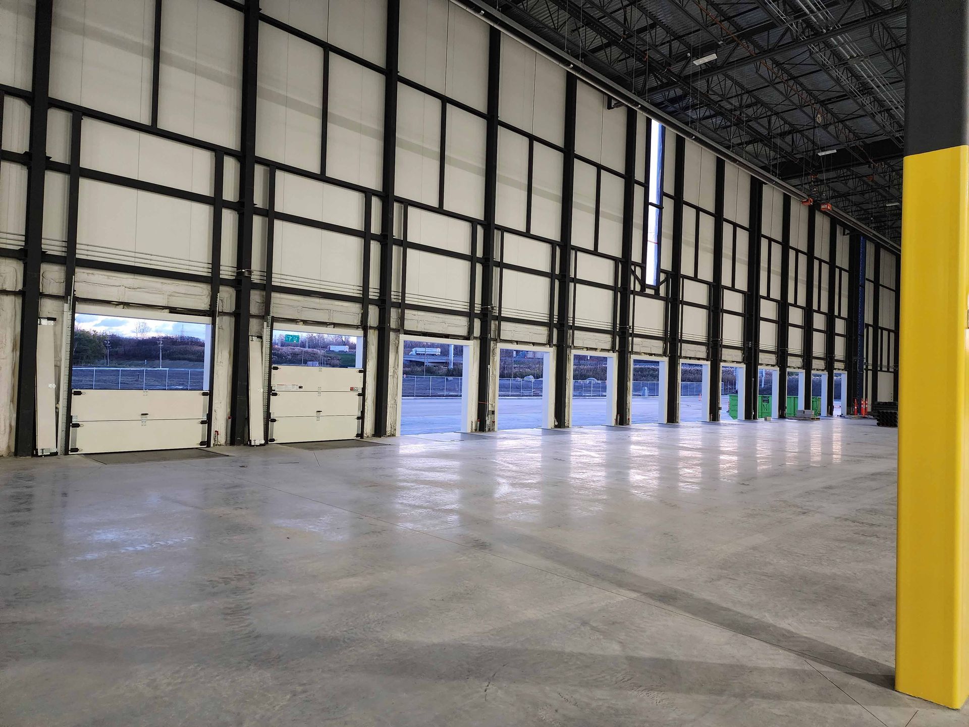 Un grand entrepôt vide avec beaucoup de portes et un poteau jaune.
