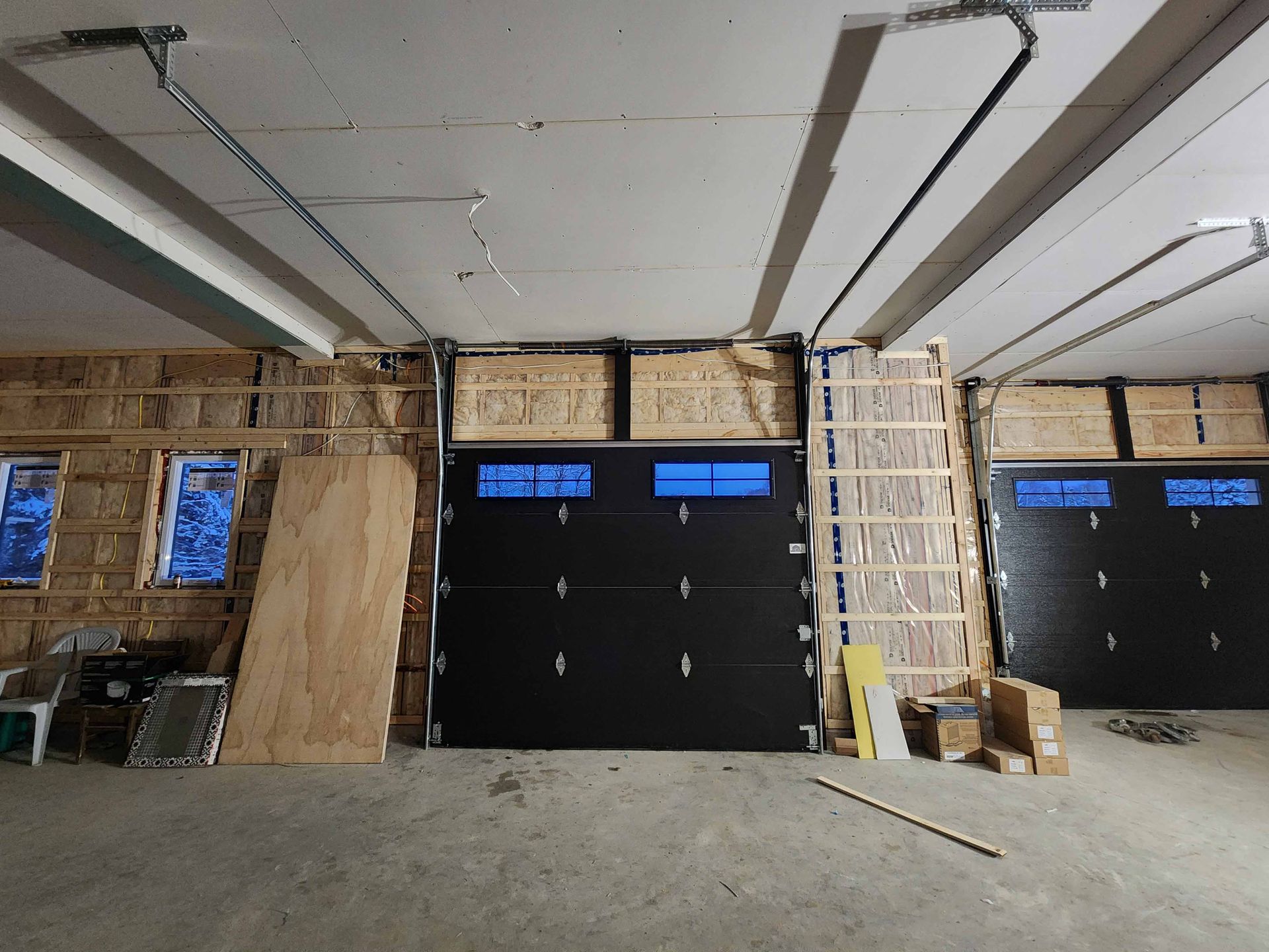 Un garage en construction avec une porte de garage noire.
