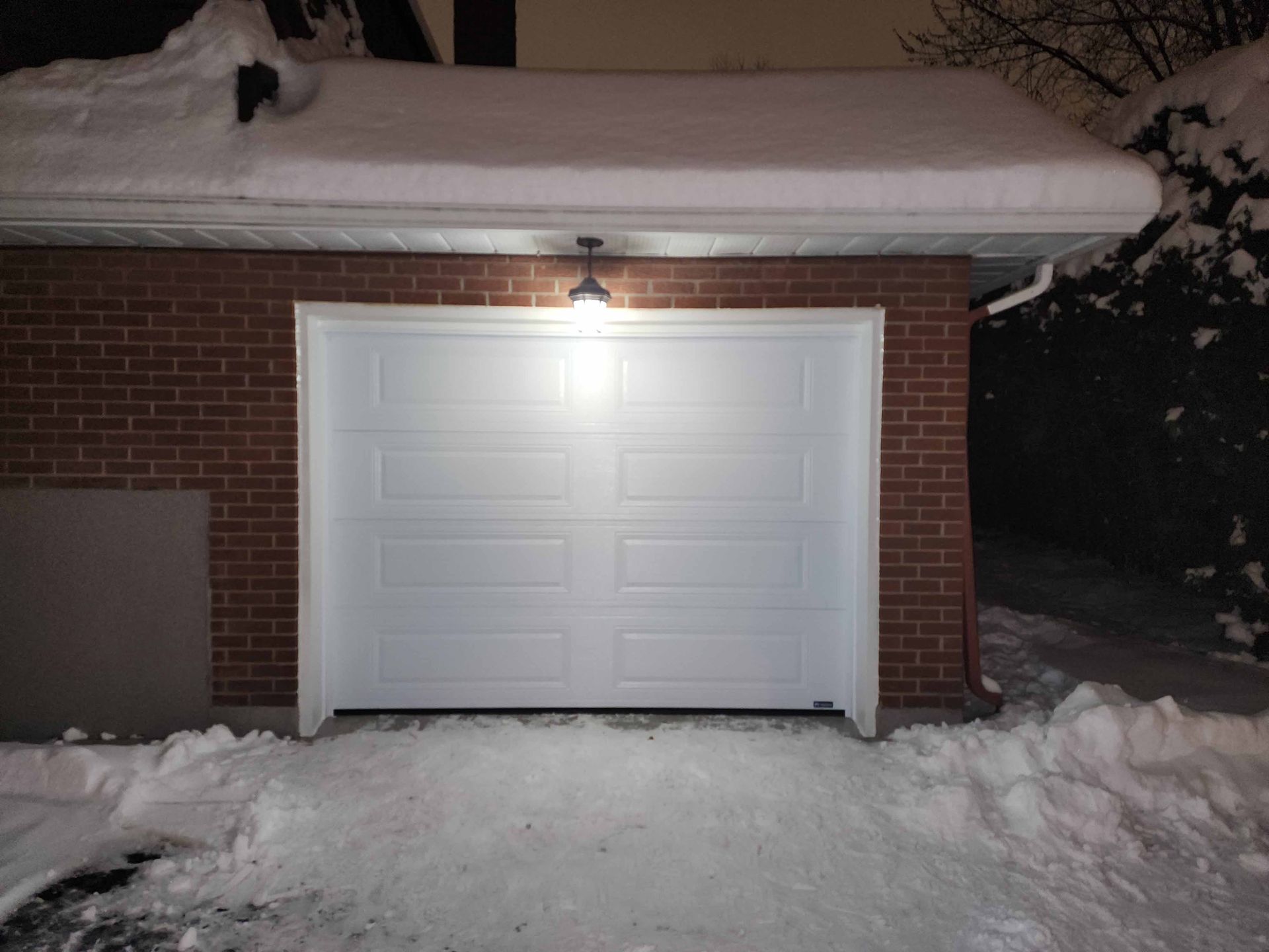 Une porte de garage blanche est ouverte dans la neige