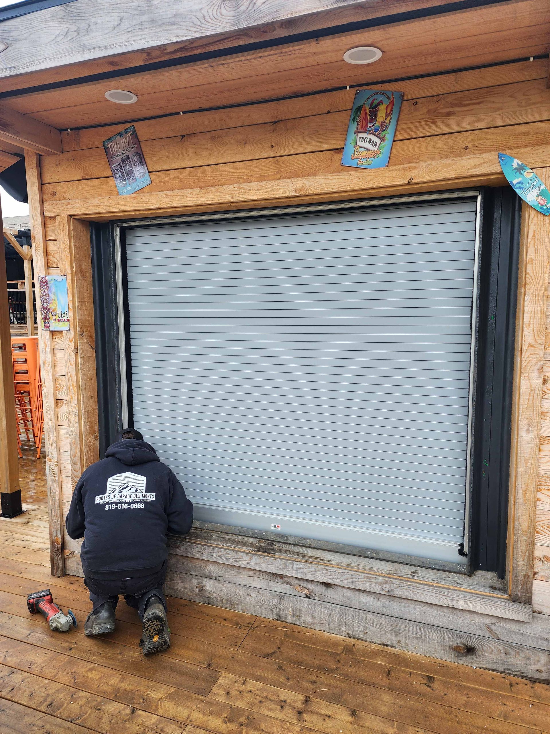 Un homme est agenouillé devant une porte de garage.