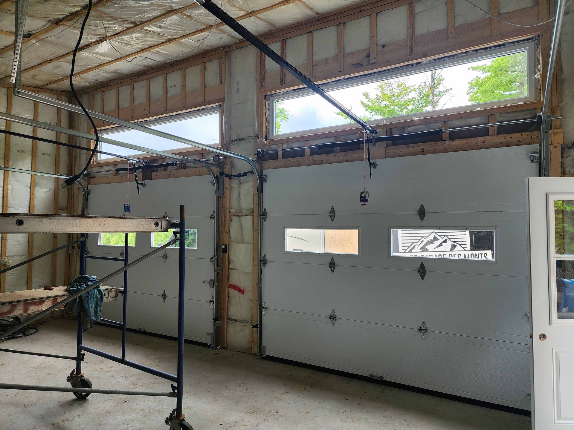 Une porte de garage est en cours d'installation dans une maison en construction.