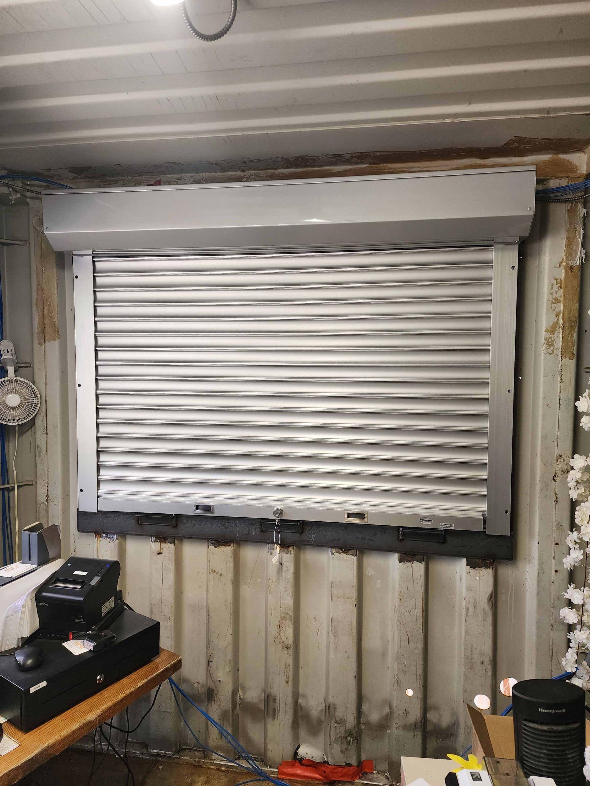 Une pièce avec un volet roulant sur la fenêtre.