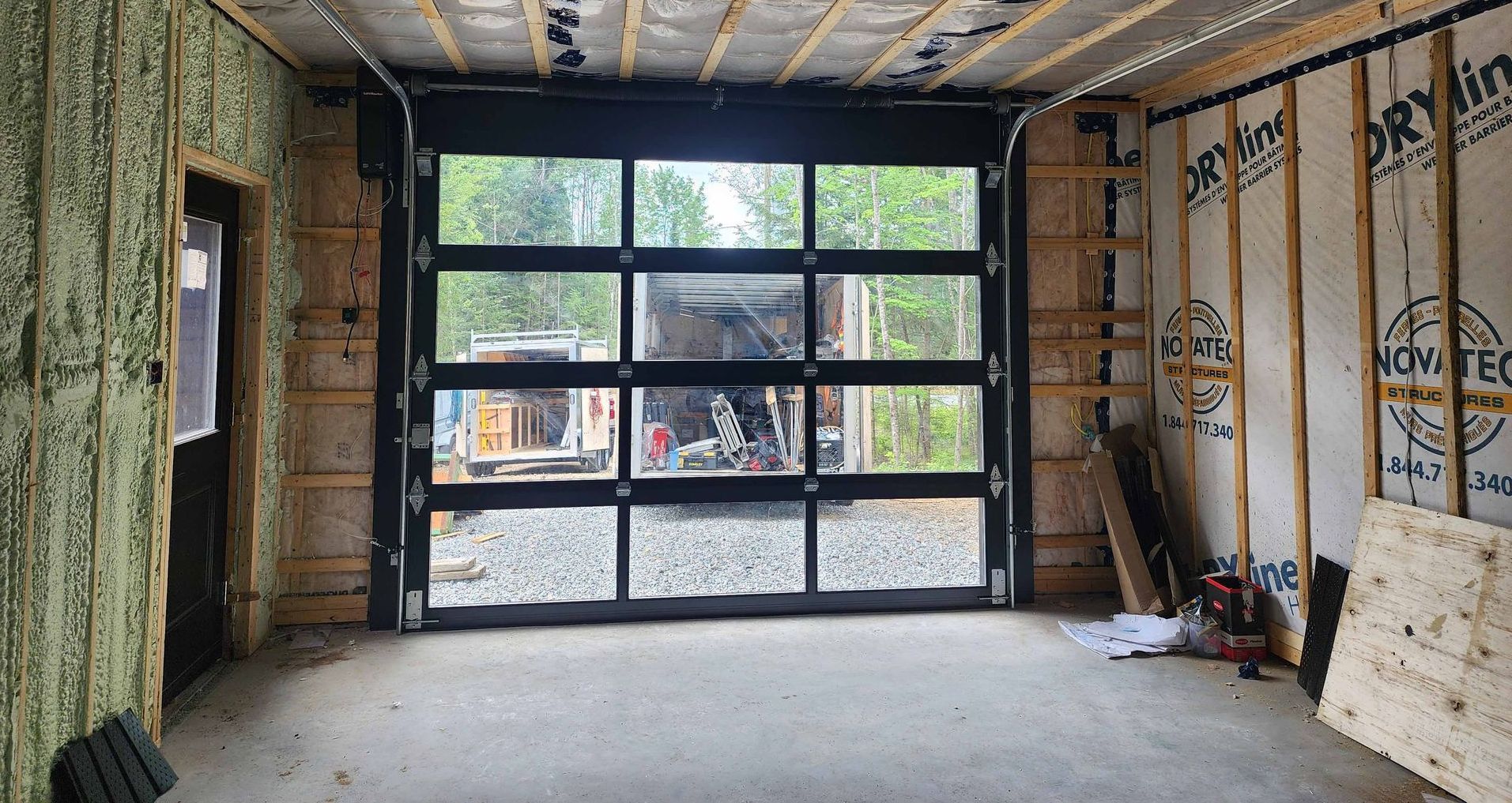 Un garage en construction avec une grande porte de garage vitrée.