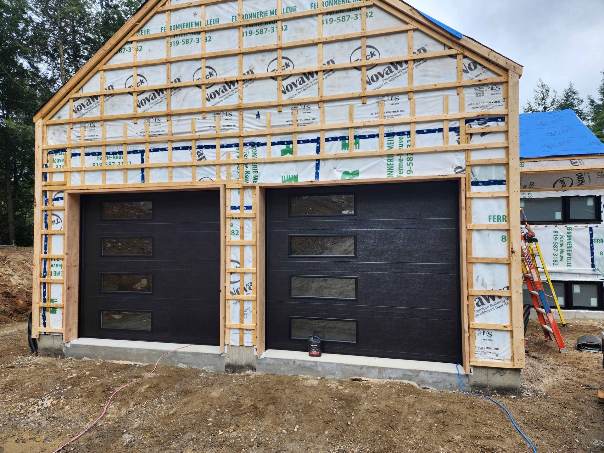 Un garage est en cours de construction avec une bâche bleue sur le toit.
