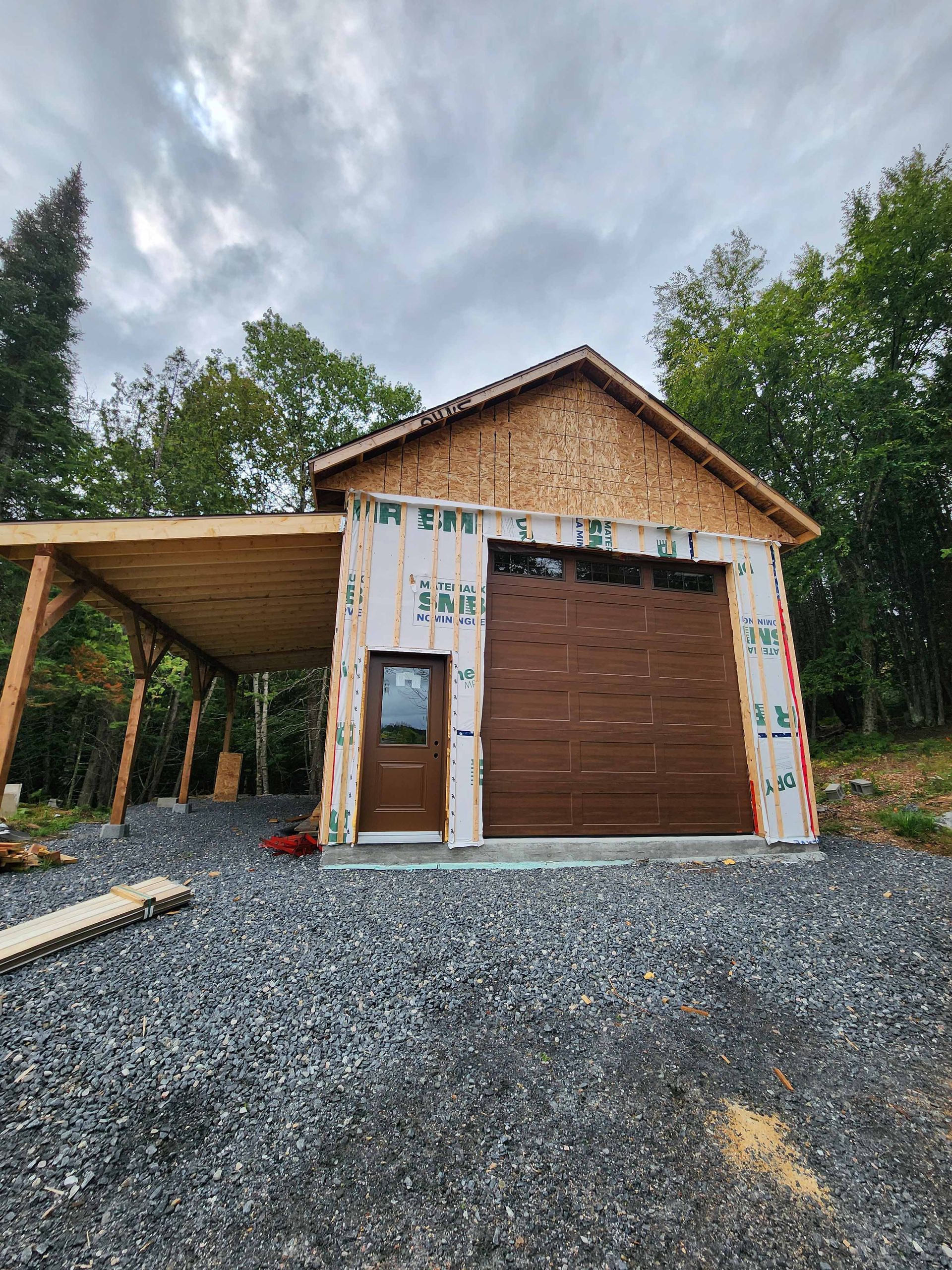 Un garage avec un abri voiture en dessous est en cours de construction.