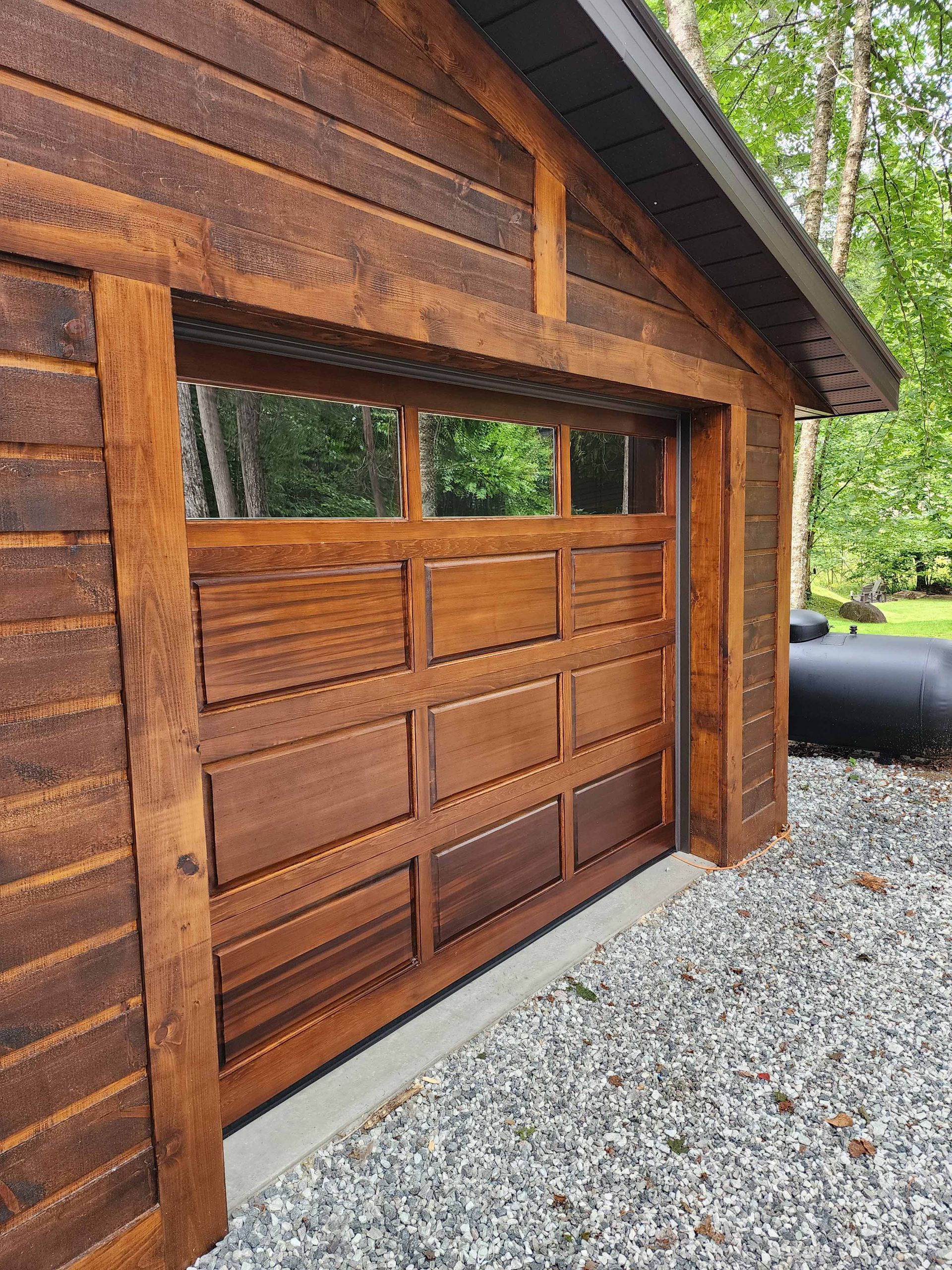 Une porte de garage en bois est posée sur une allée de gravier.