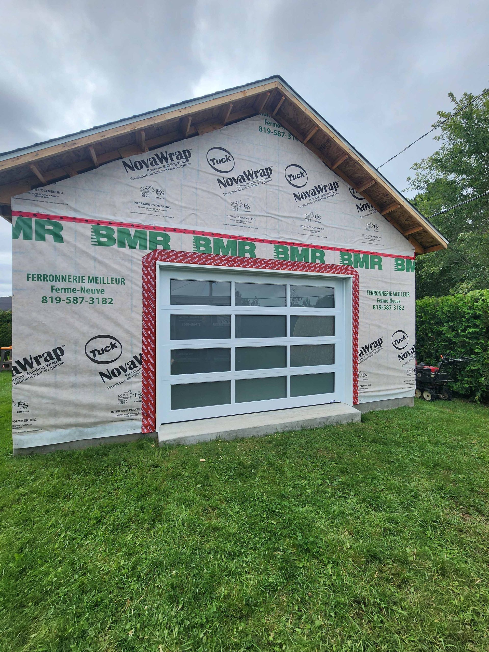 Un garage avec une porte coulissante en verre se trouve au milieu d'un champ verdoyant.