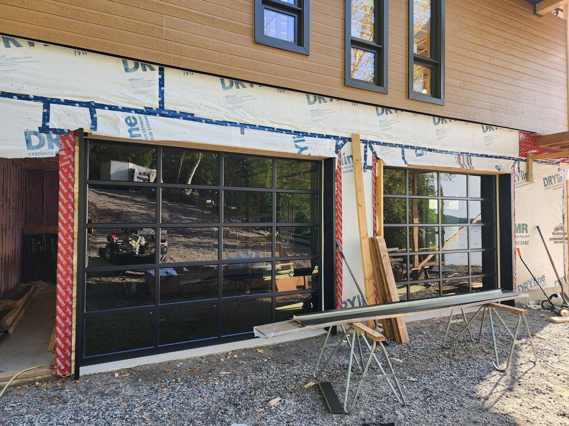 Une porte de garage est en cours d'installation sur le côté d'une maison en construction.