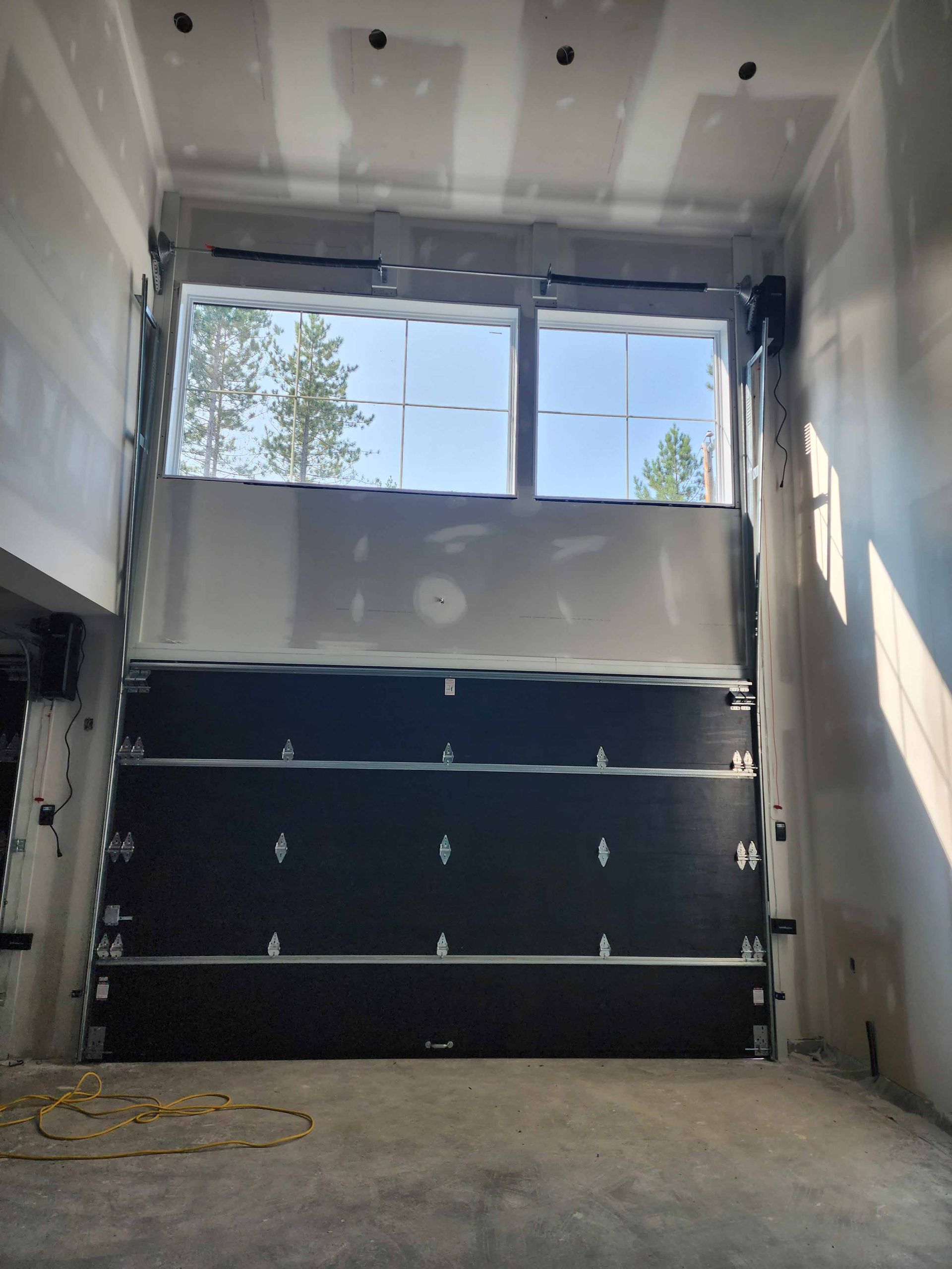 Un garage avec une porte de garage noire et une fenêtre