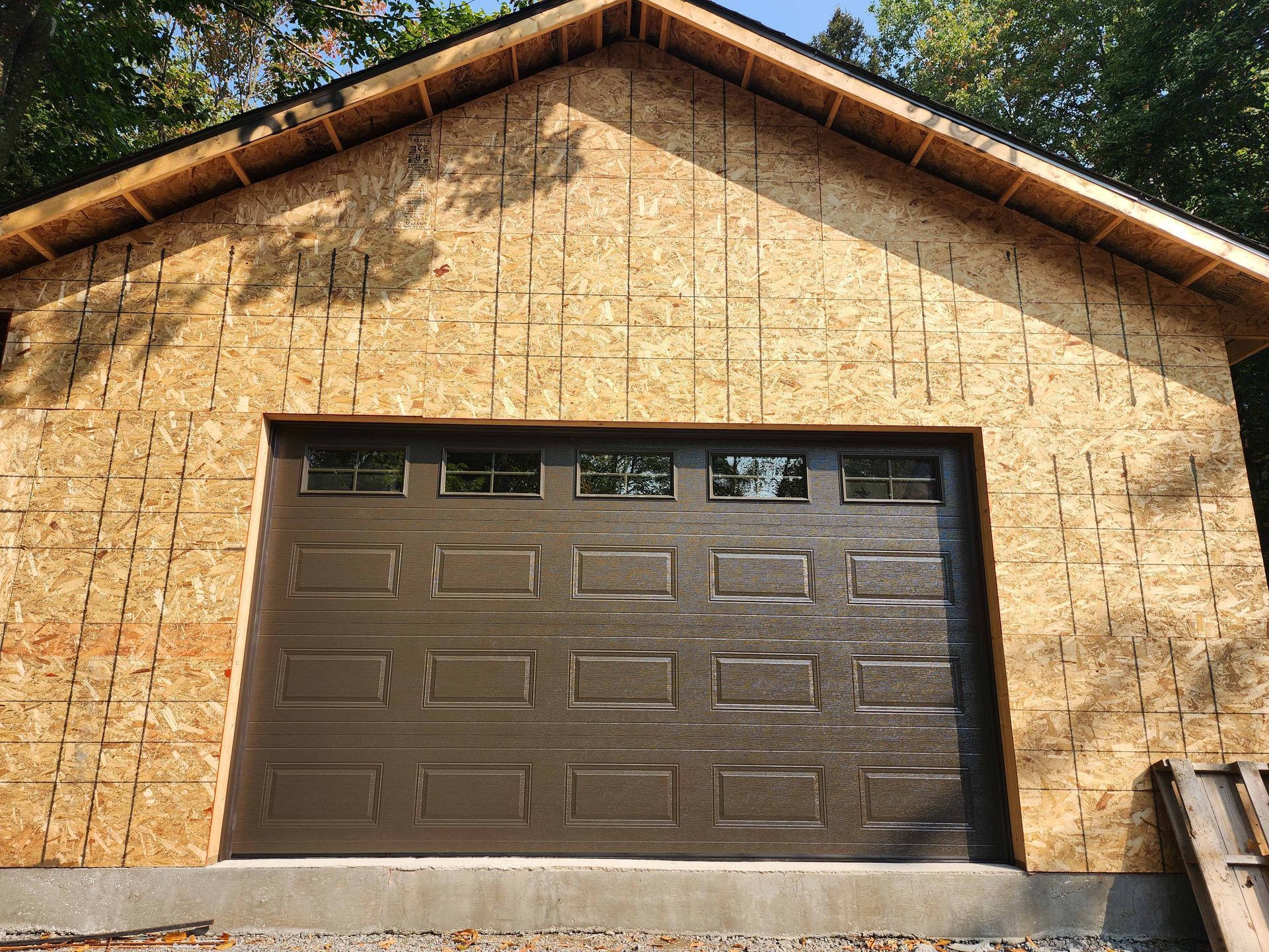 Une porte de garage est en cours d'installation sur une maison en construction.
