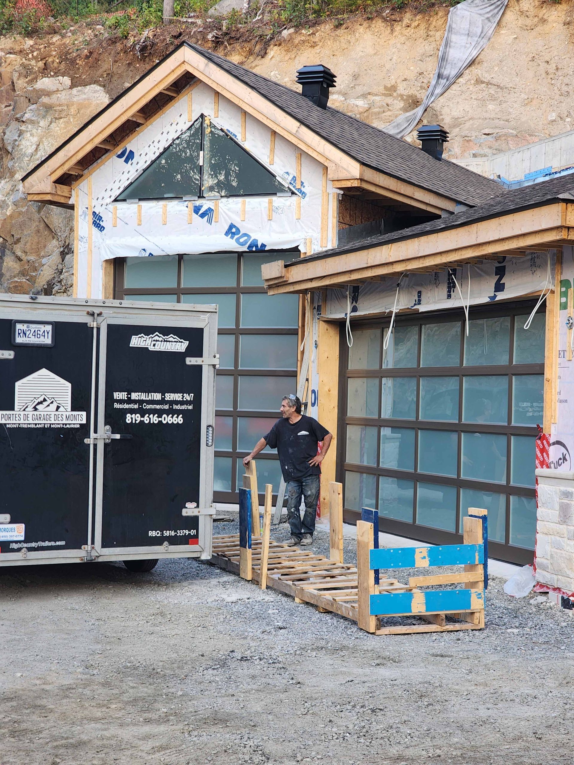 Un homme se tient devant une porte de garage en cours d'installation.
