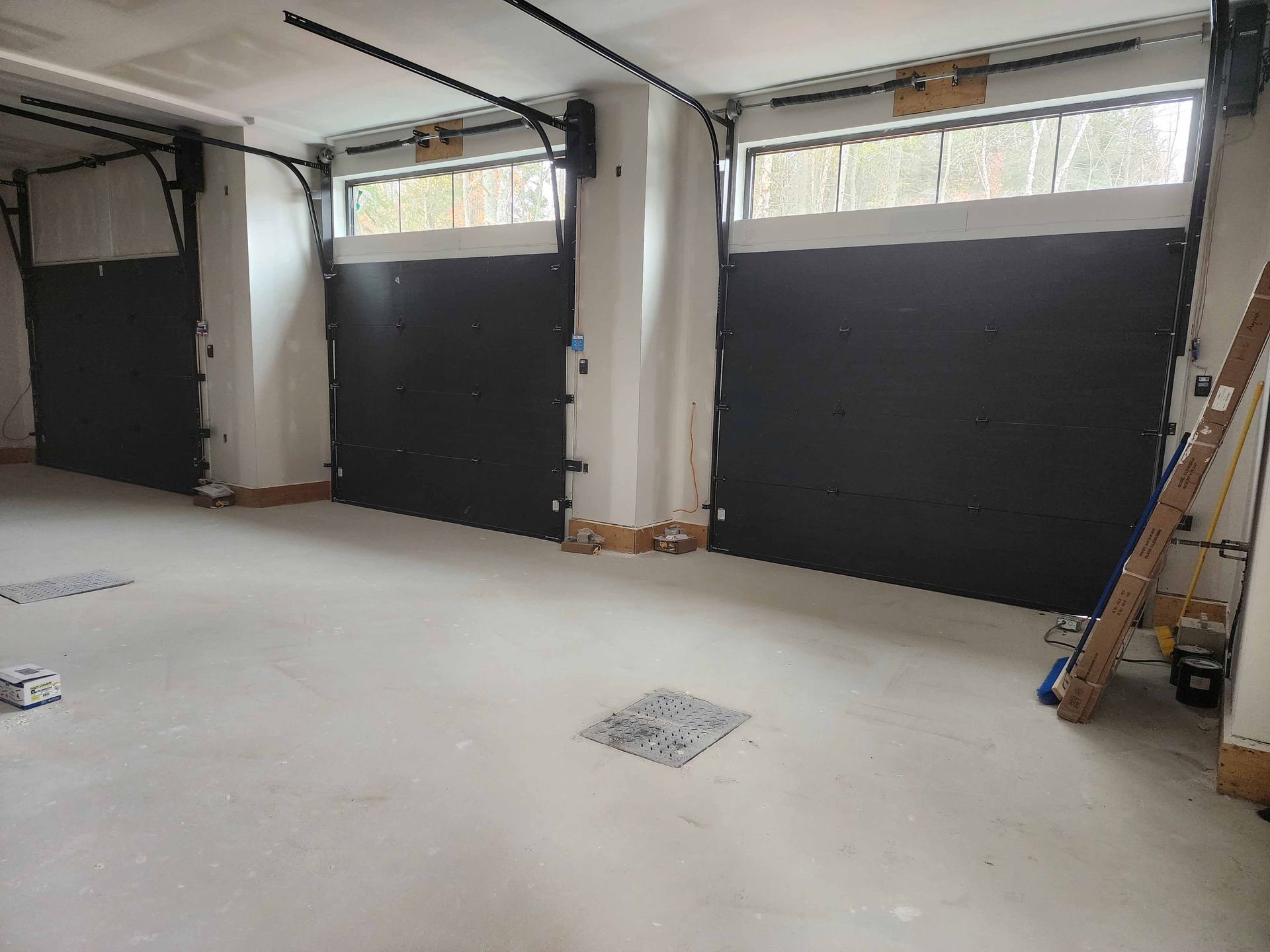 Un garage avec trois portes de garage noires et une fenêtre.