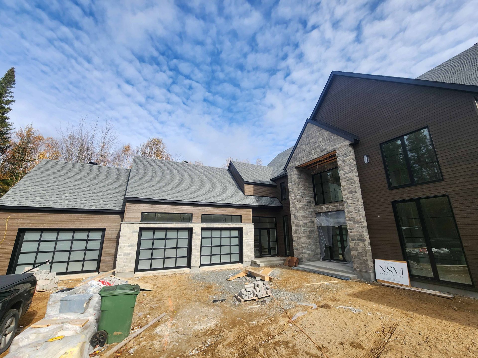 Une grande maison est en construction avec beaucoup de fenêtres et de portes de garage.