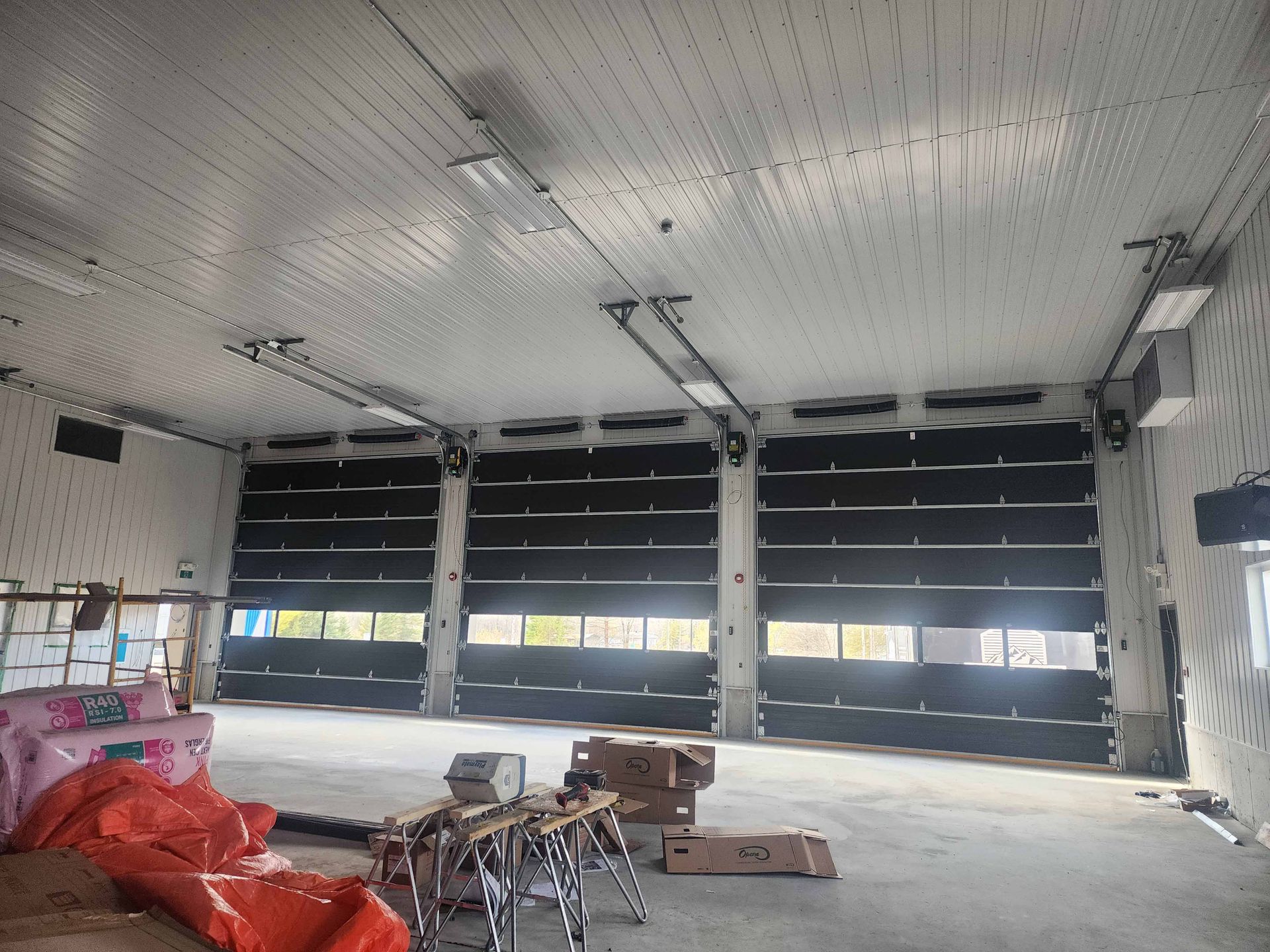 Un grand entrepôt avec beaucoup de portes et de boîtes au sol.