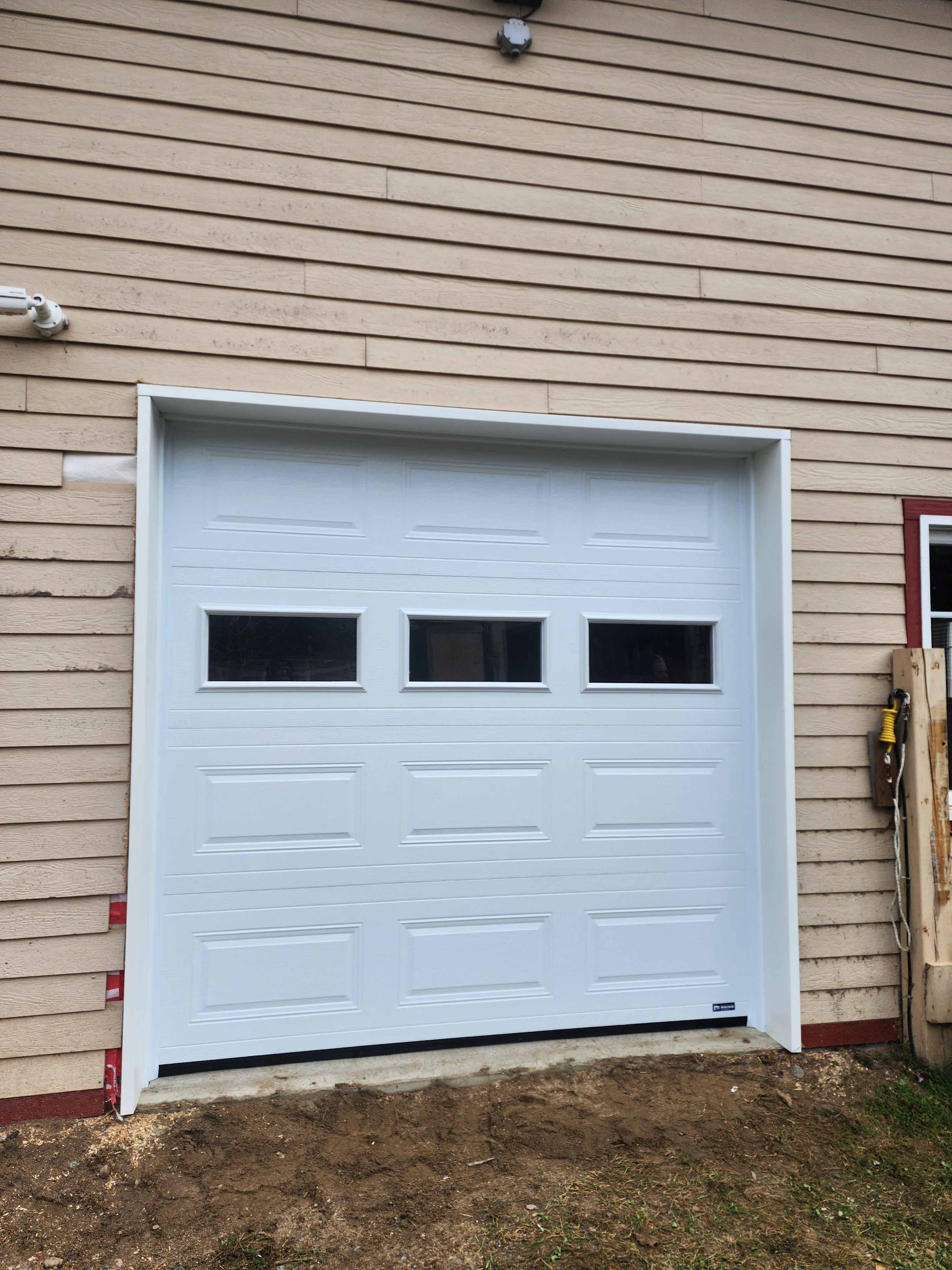 Une porte de garage blanche se trouve sur le côté d'une maison.