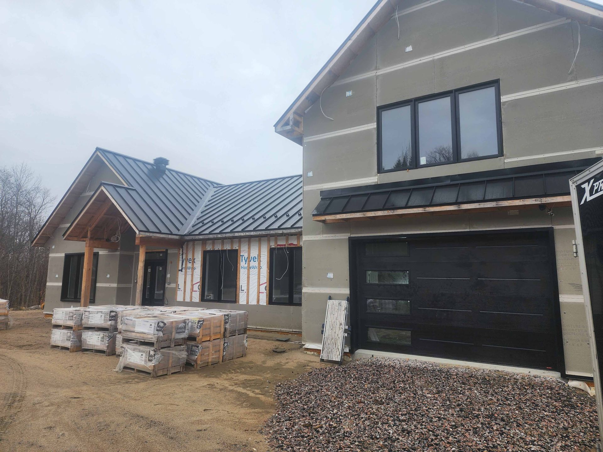 Une maison en construction avec une porte de garage et beaucoup de fenêtres.