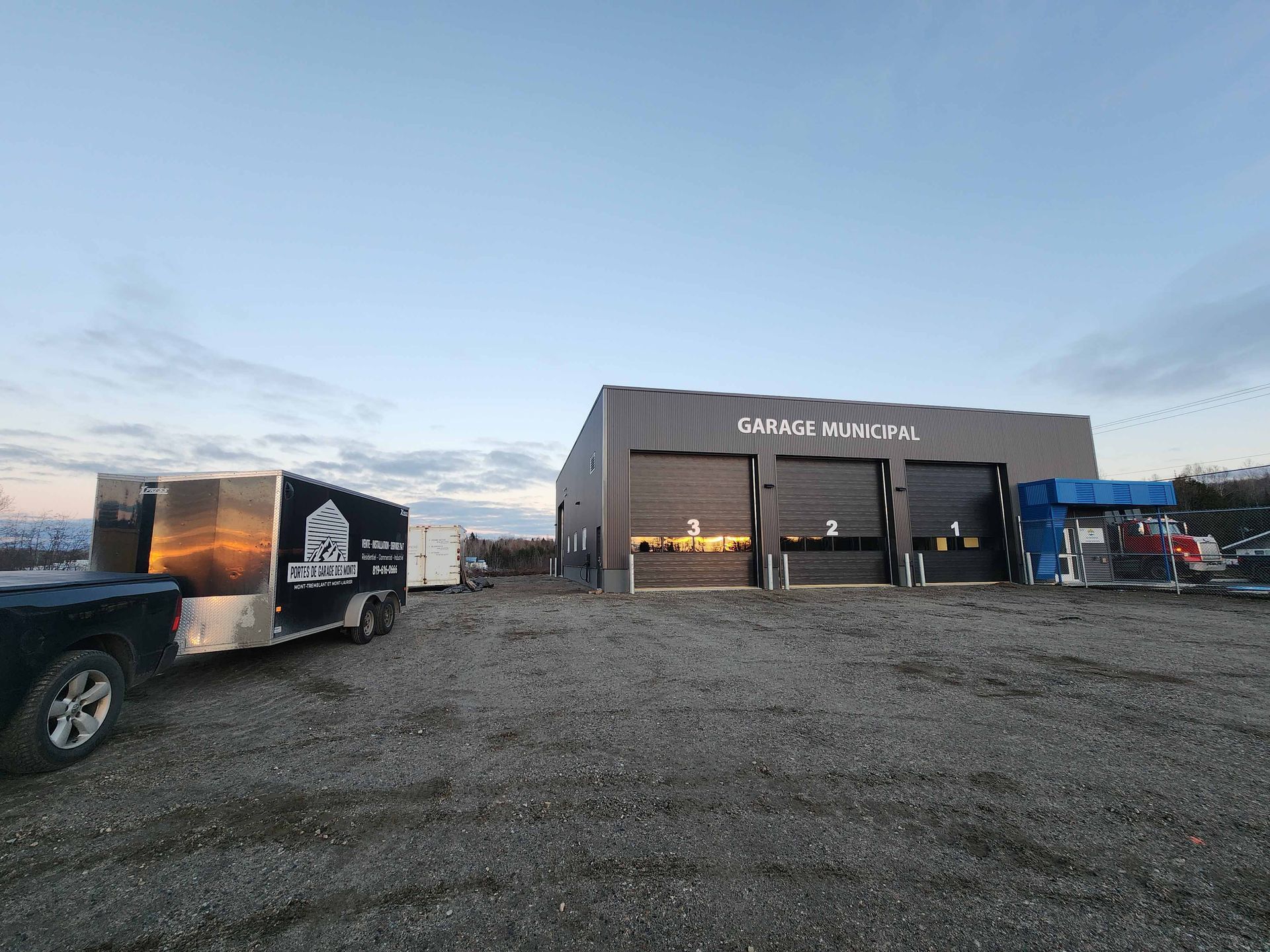 Un camion et une remorque sont garés devant un grand bâtiment.