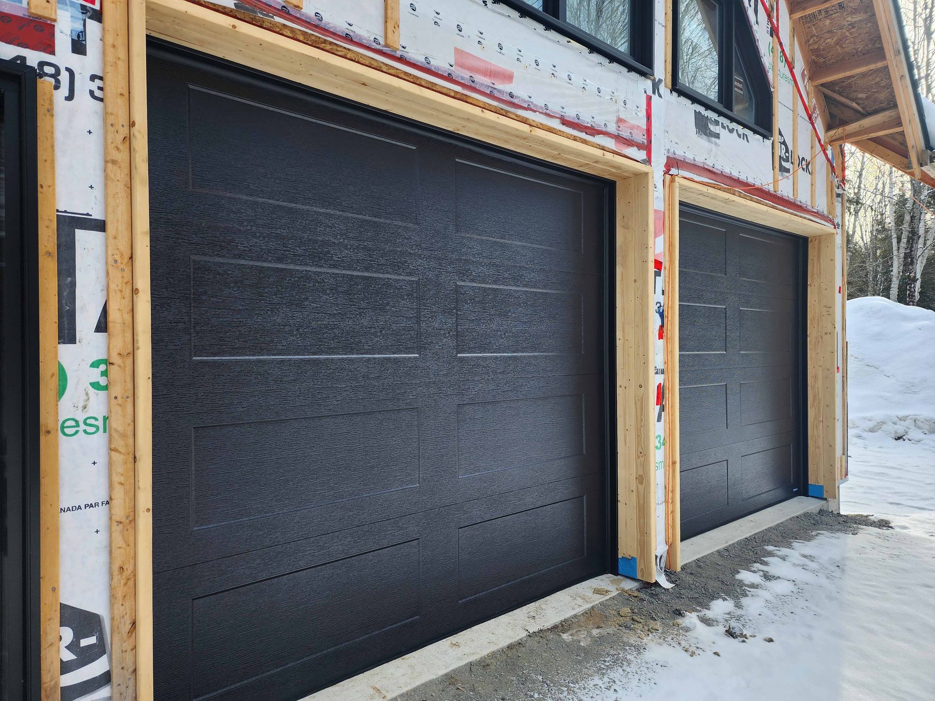 Une porte de garage est en cours d'installation sur le côté d'une maison.
