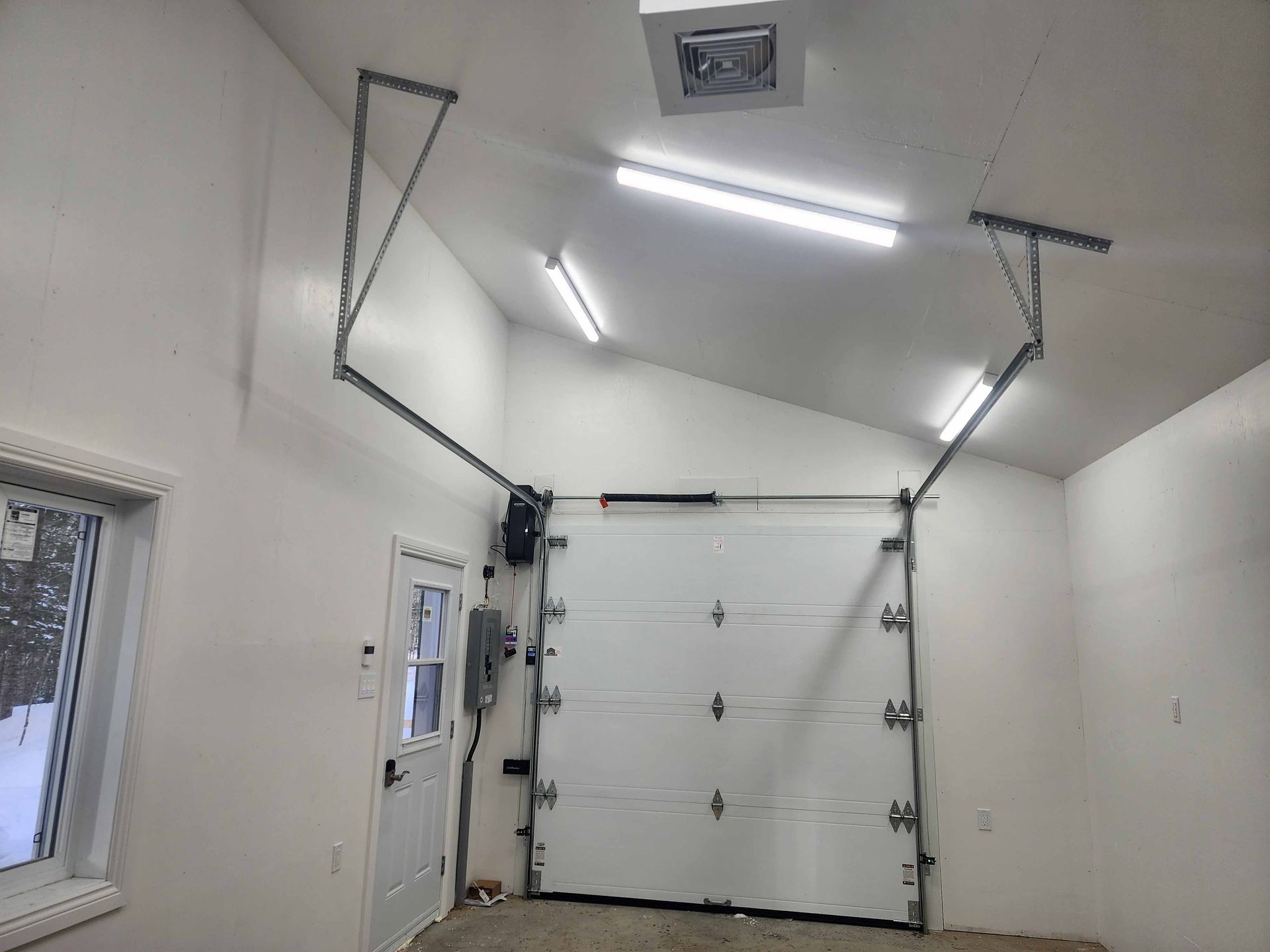 Garage blanc avec une porte fermée, un ouvre-porte automatique attaché et des bras de support ouverts.