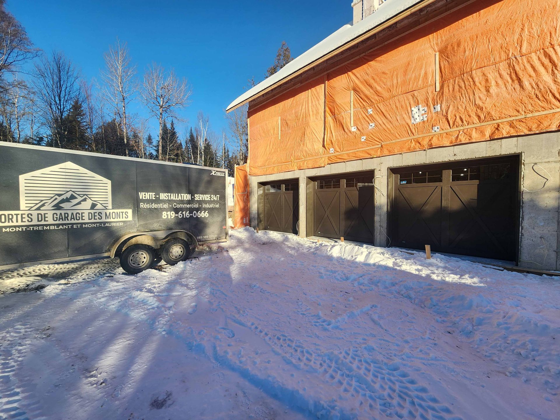 Une remorque est garée devant un garage en construction.
