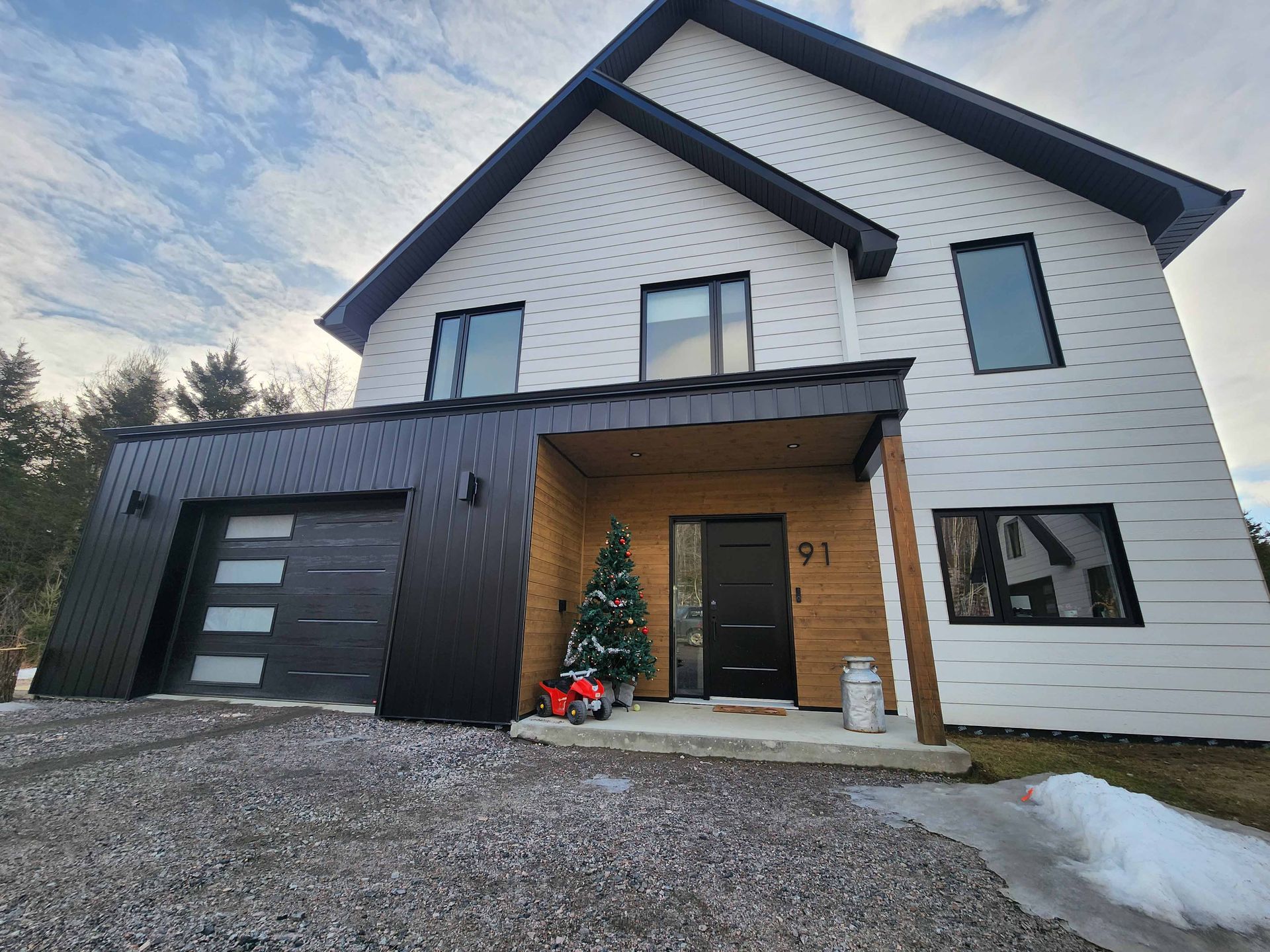 Une maison en noir et blanc avec un sapin de Noël devant.