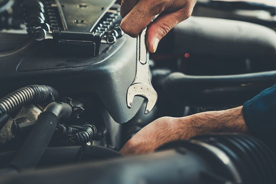 A man is working on a car engine with a wrench.