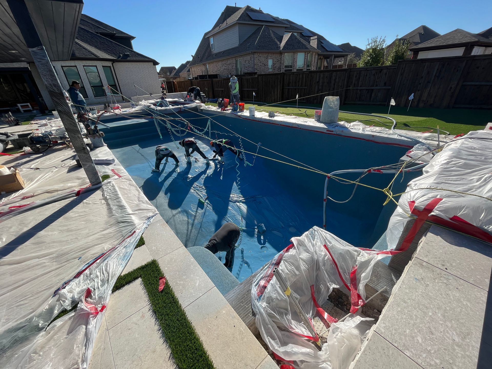 A large swimming pool is being built in a backyard.