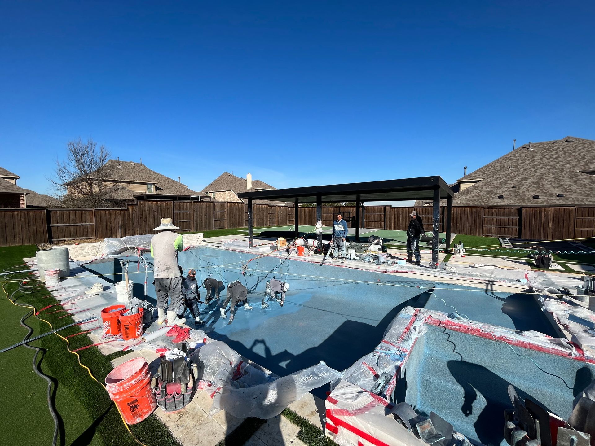 A man is working on a swimming pool in a backyard.