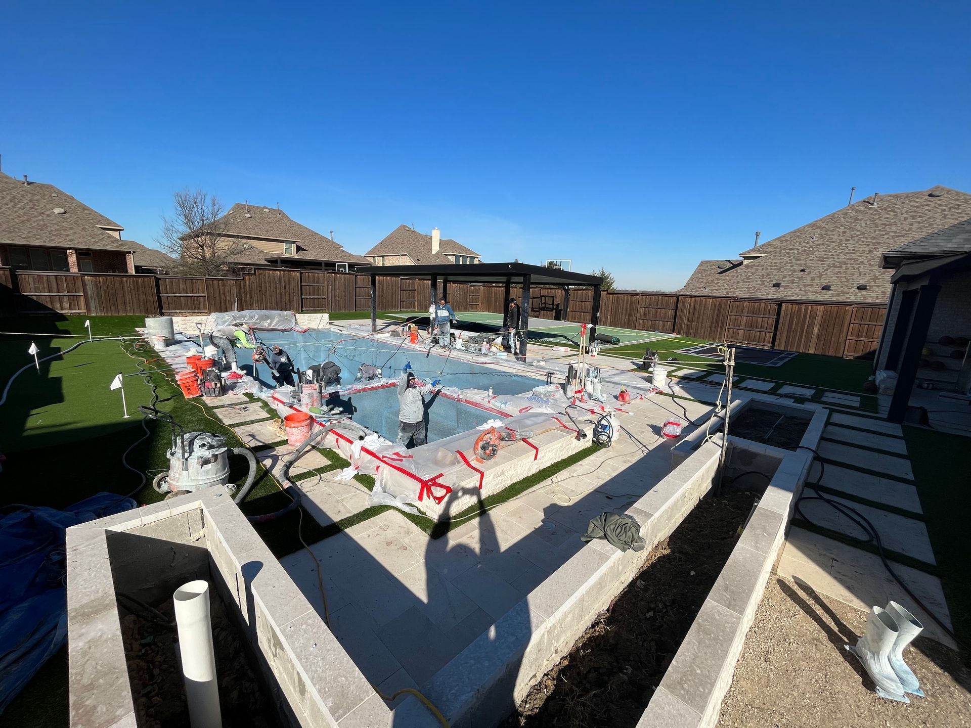 A large swimming pool is being built in the backyard of a house.
