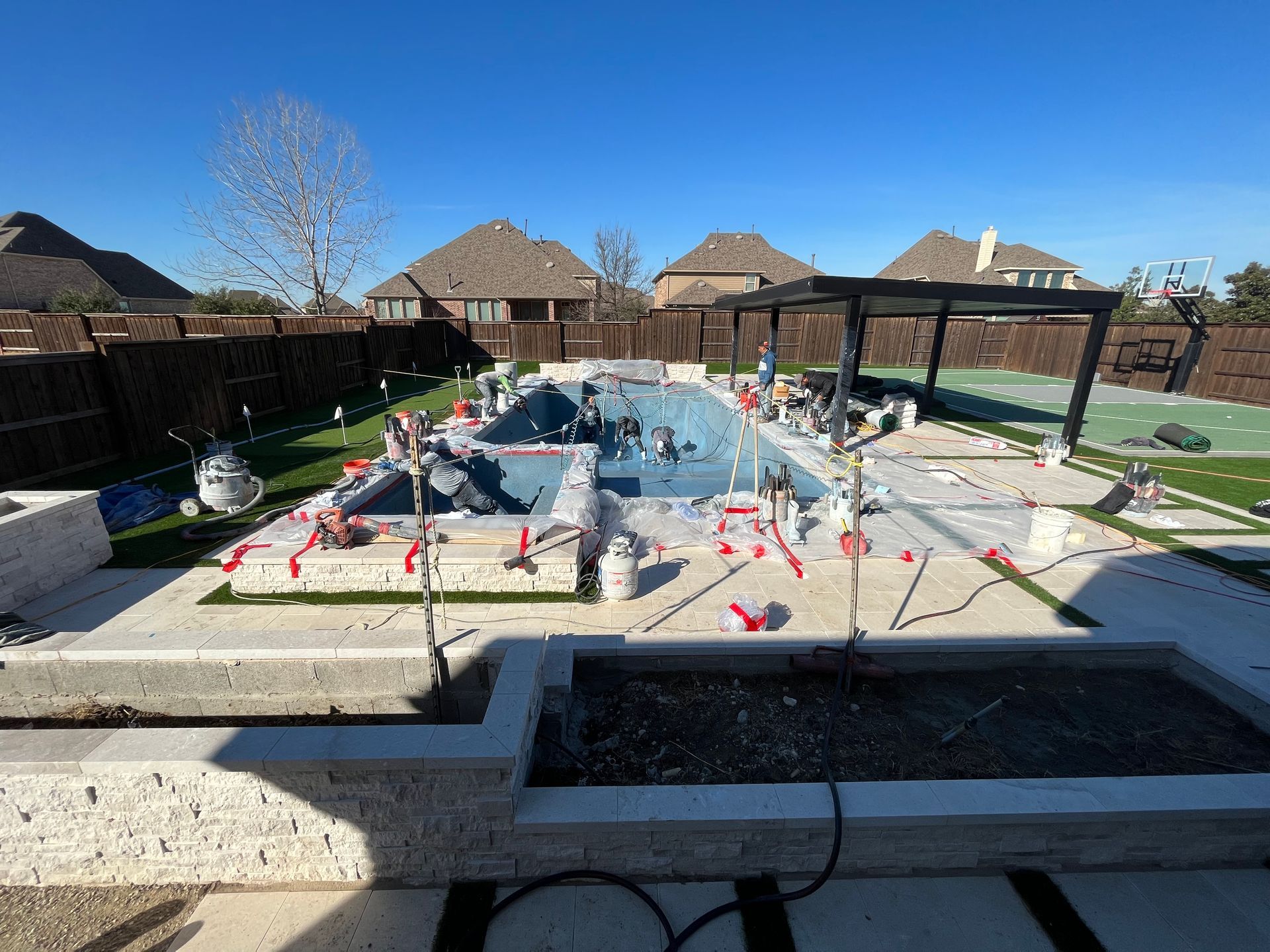A large swimming pool is being built in a backyard.