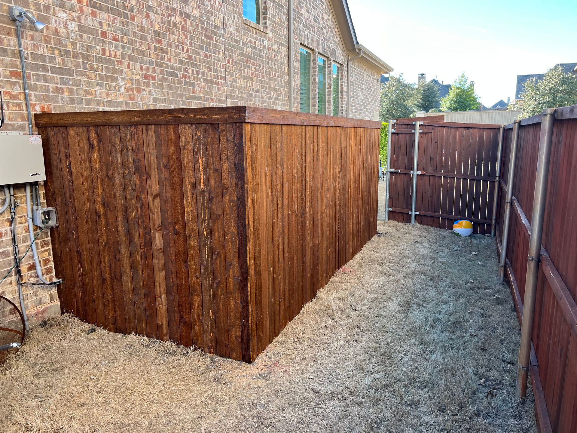 A wooden fence is in the backyard of a house.