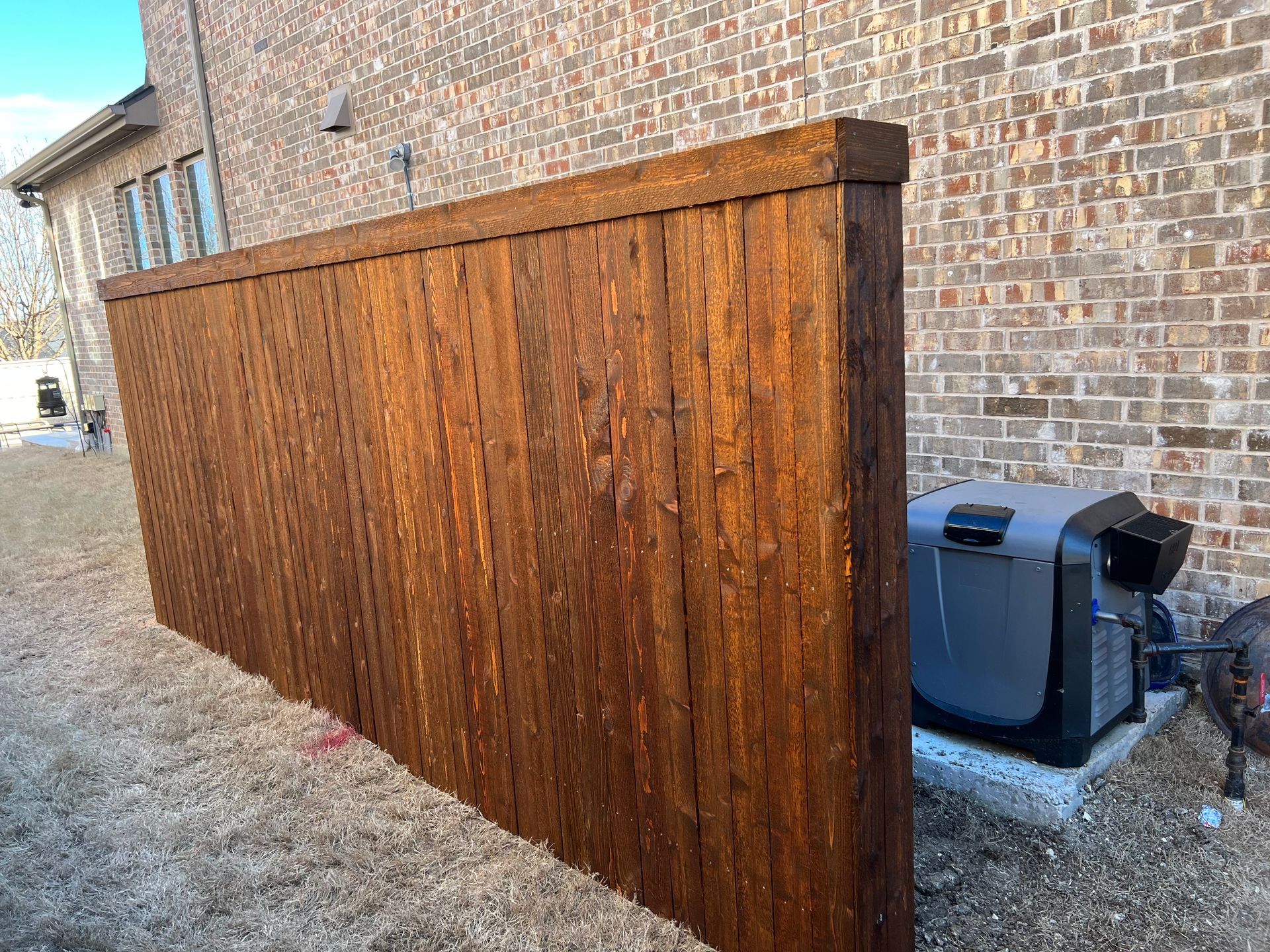 A wooden fence is sitting in front of a brick building.