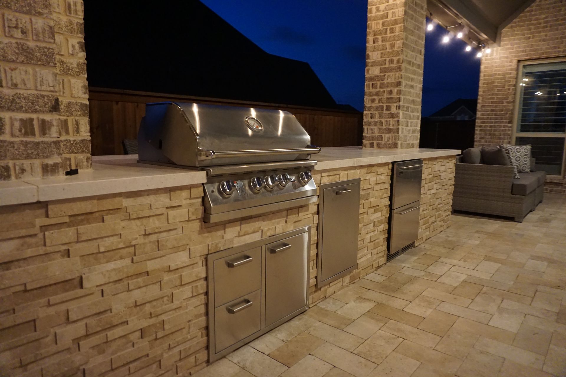 An outdoor kitchen with a grill and a stainless steel dishwasher.