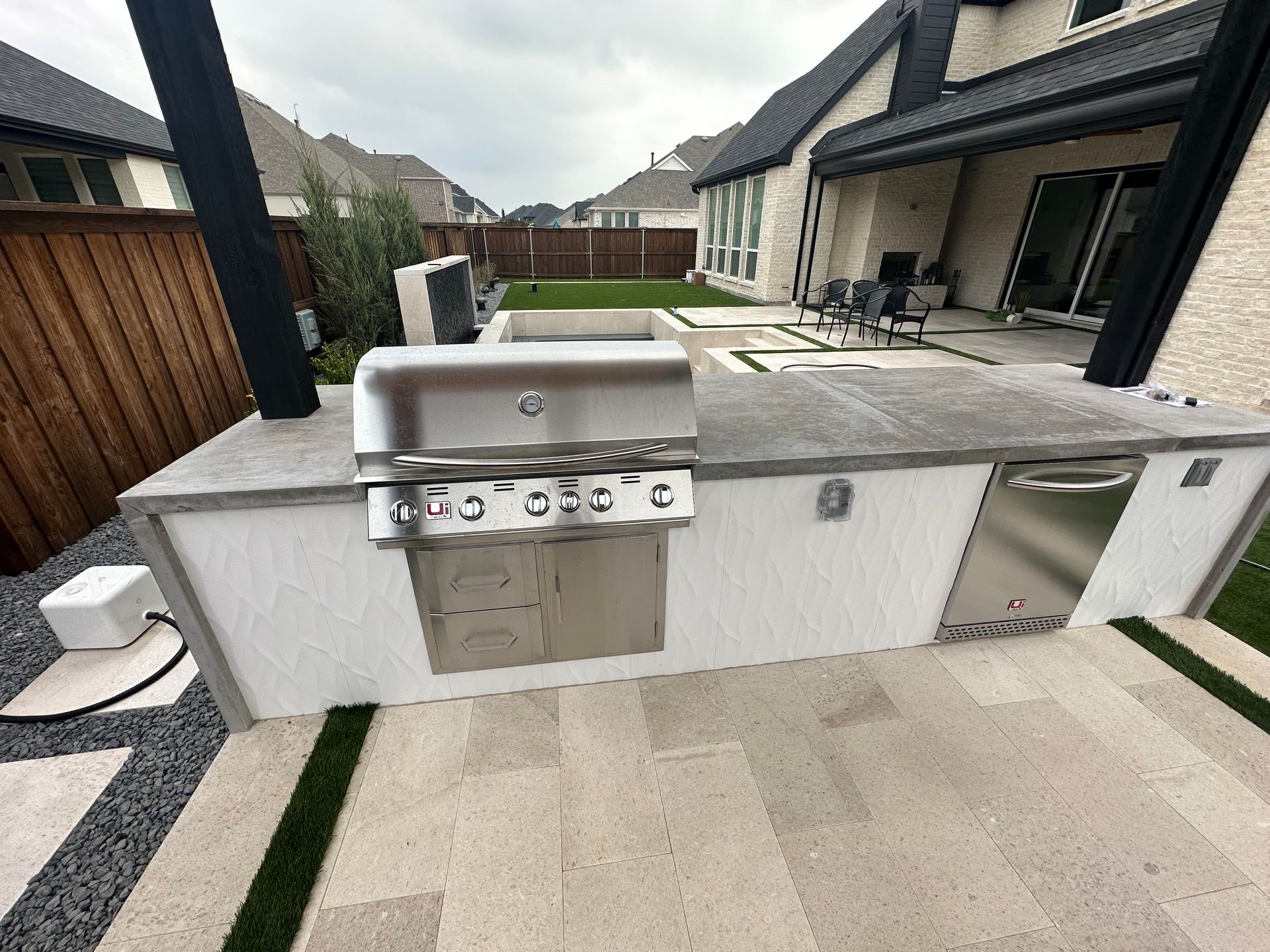 A stainless steel grill is sitting on top of a white counter in front of a house.