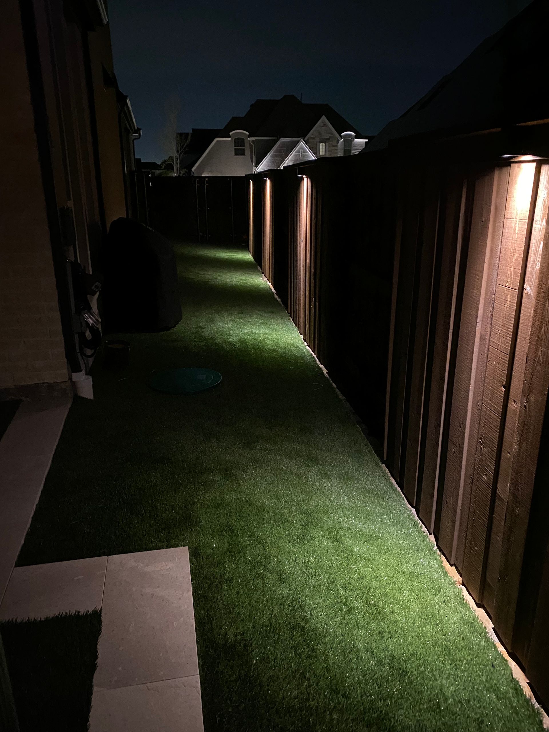 A walkway with lights on the side of it and a wooden fence.