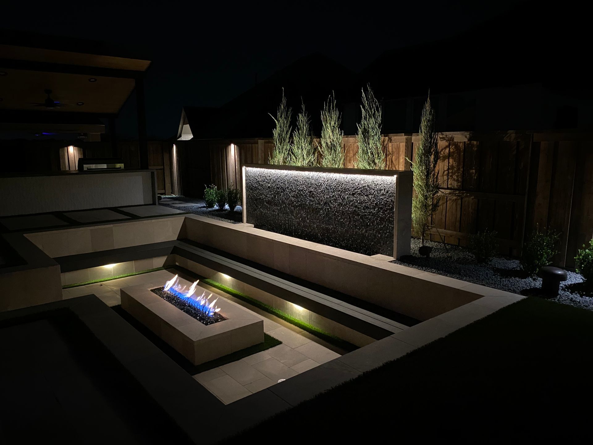 A fire pit is lit up at night in a backyard.
