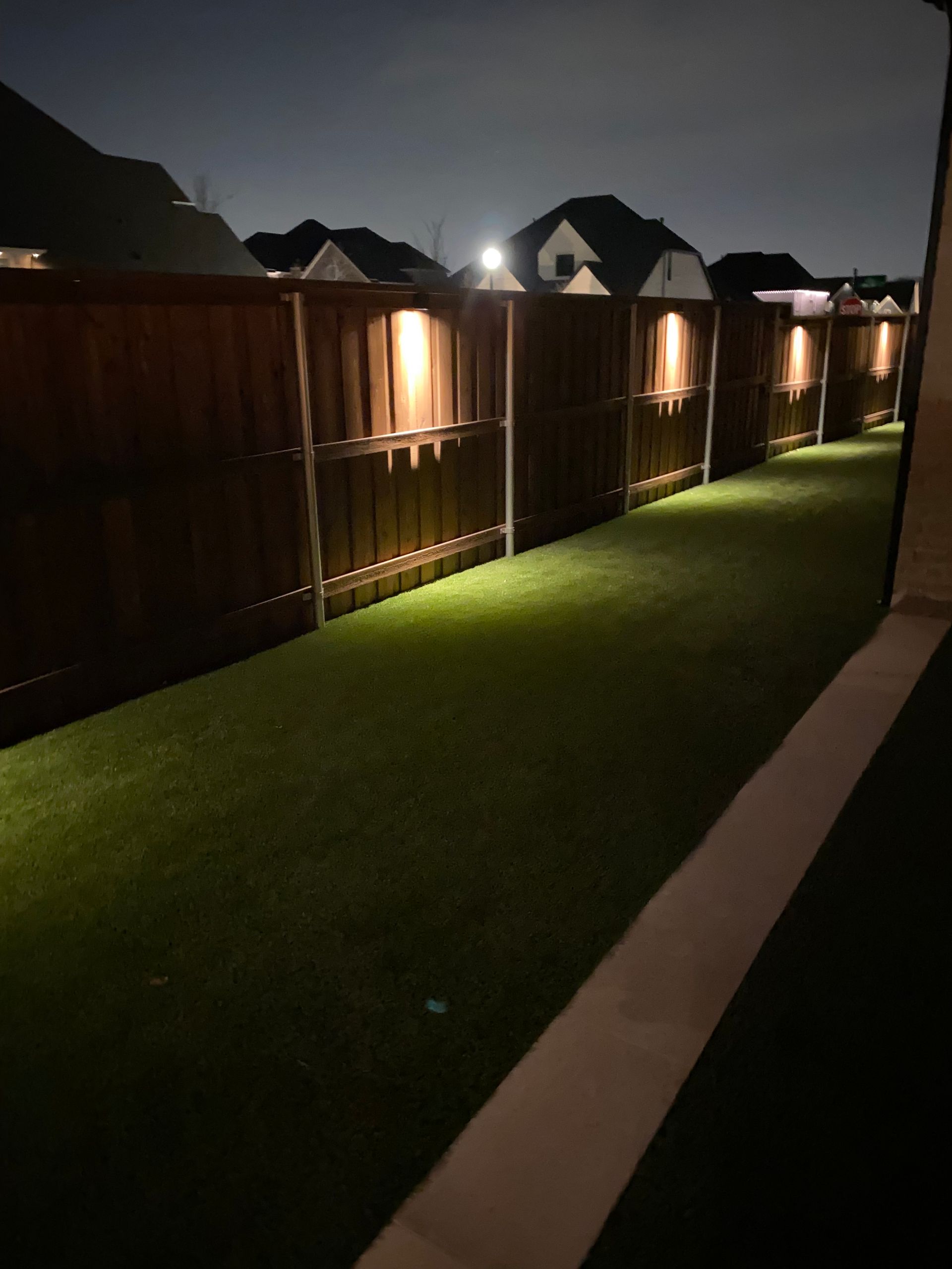 A wooden fence surrounds a grassy area at night