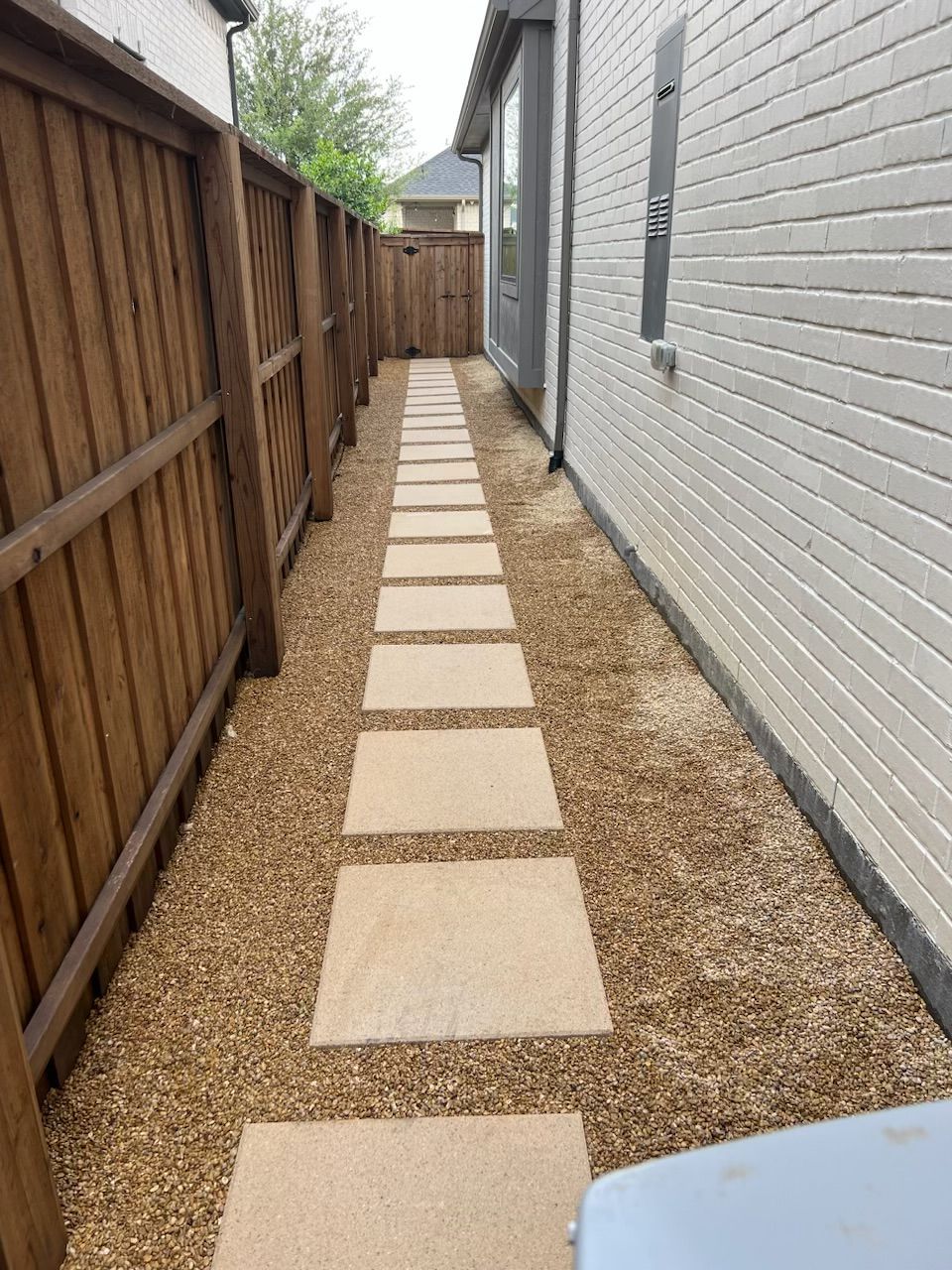 A walkway leading to a house with a wooden fence.