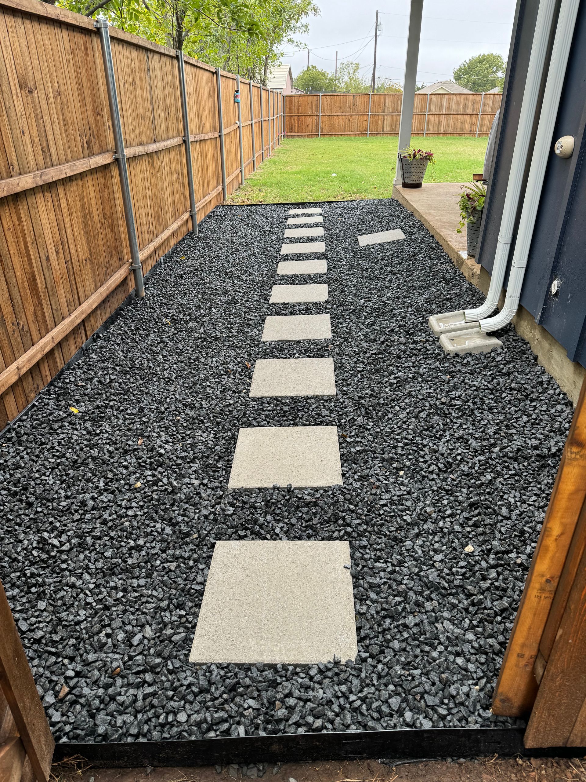 A walkway leading to a backyard with gravel and stepping stones.