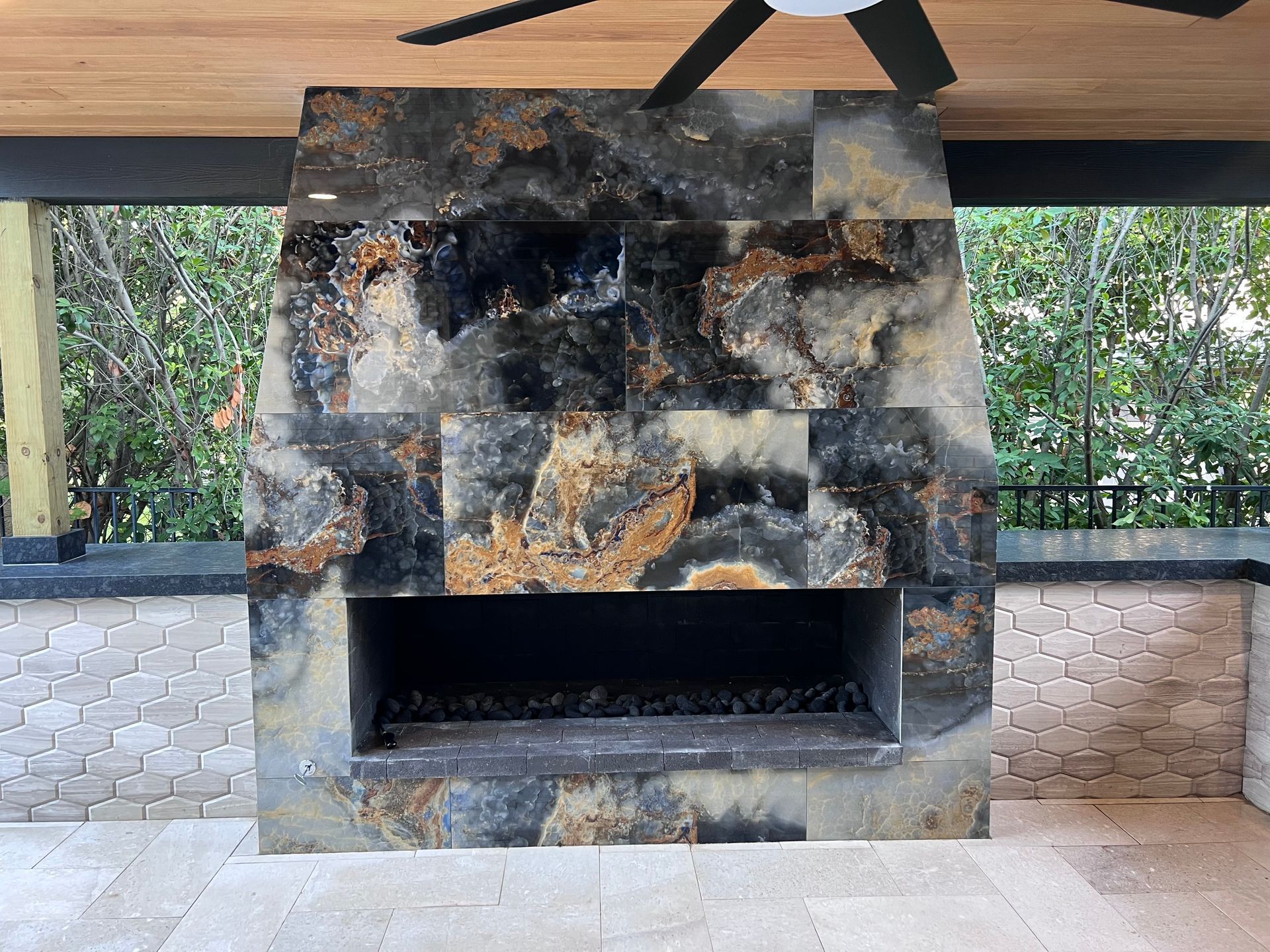 A fireplace with a ceiling fan above it.
