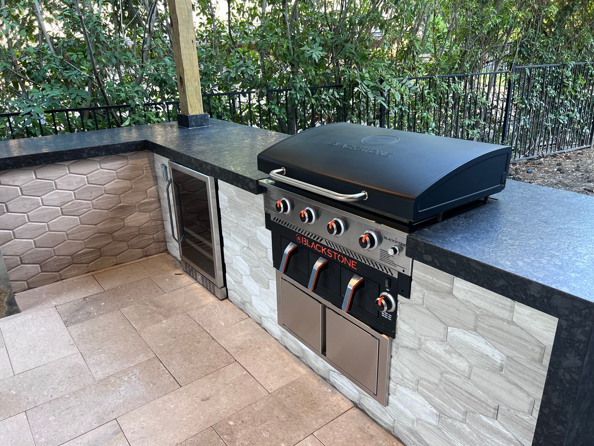 A grill is sitting on top of a counter in an outdoor kitchen.
