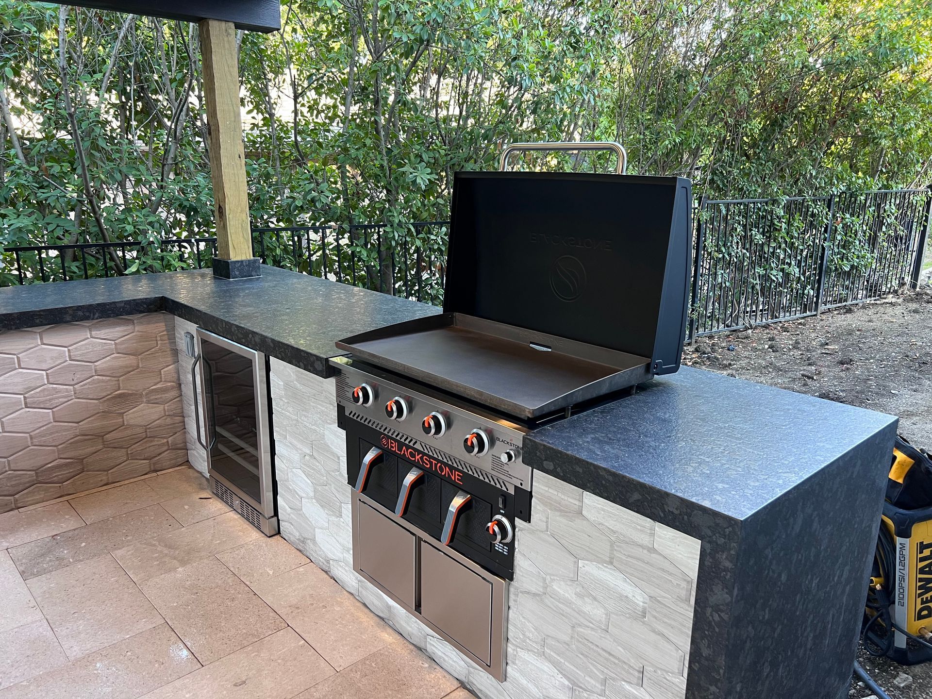 A grill is sitting on top of a counter in an outdoor kitchen.