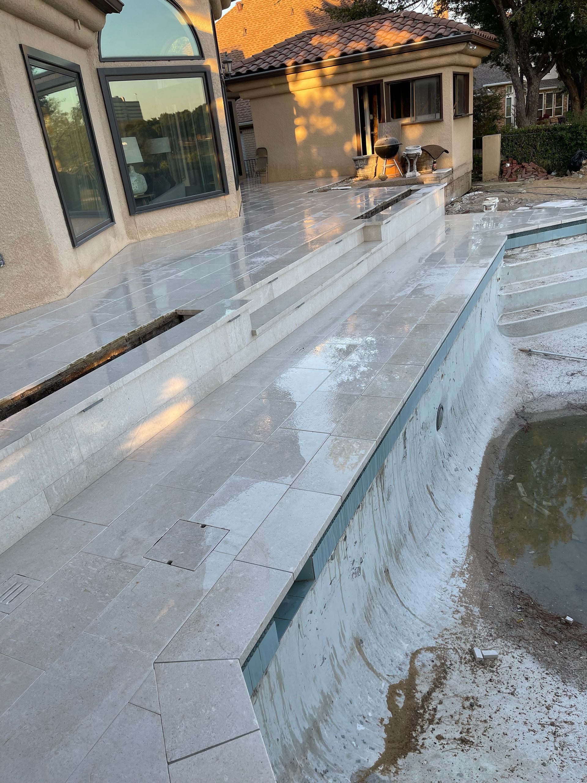 A swimming pool is being remodeled in front of a house.