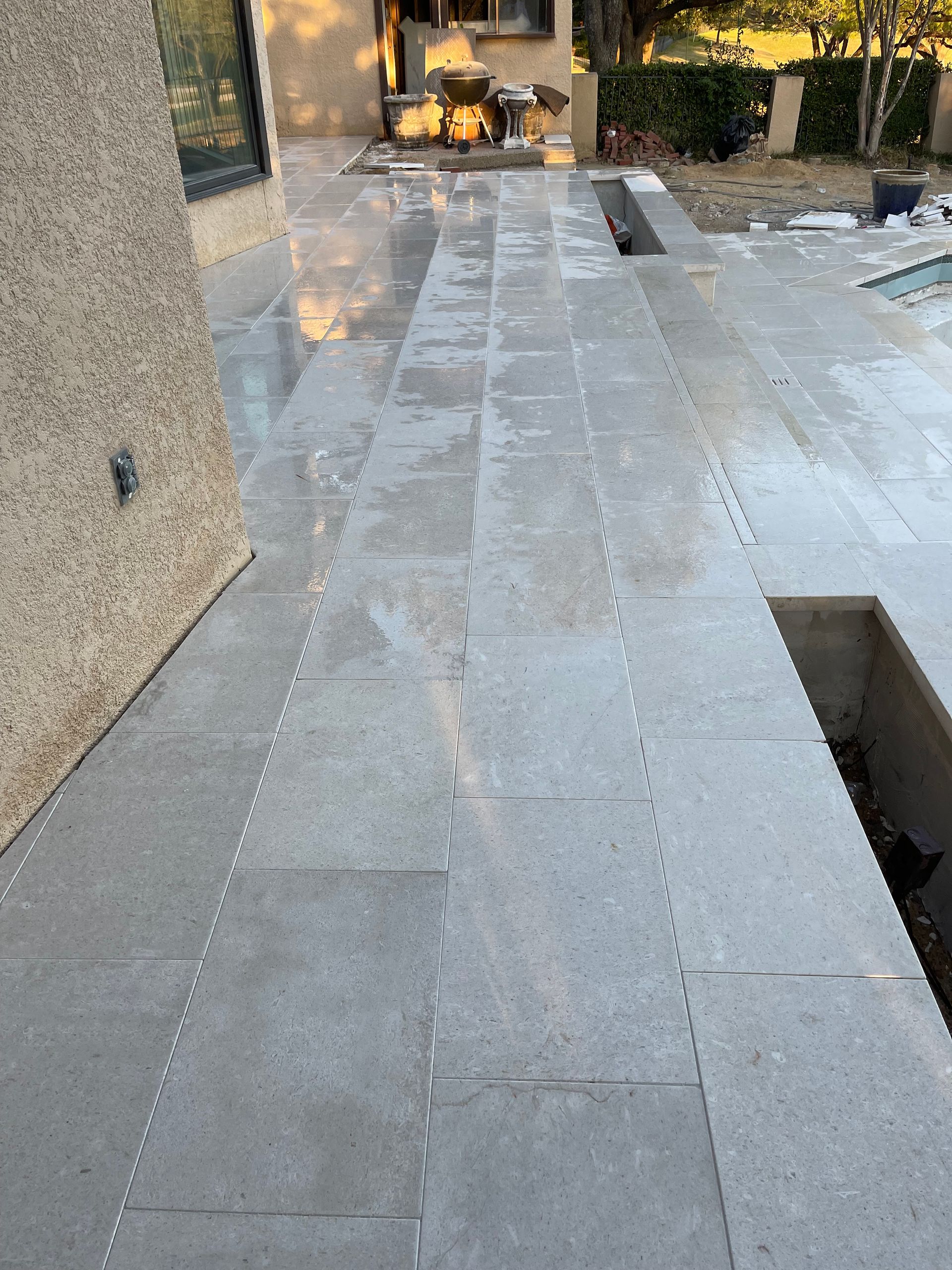 A tiled walkway leading to a pool next to a building.