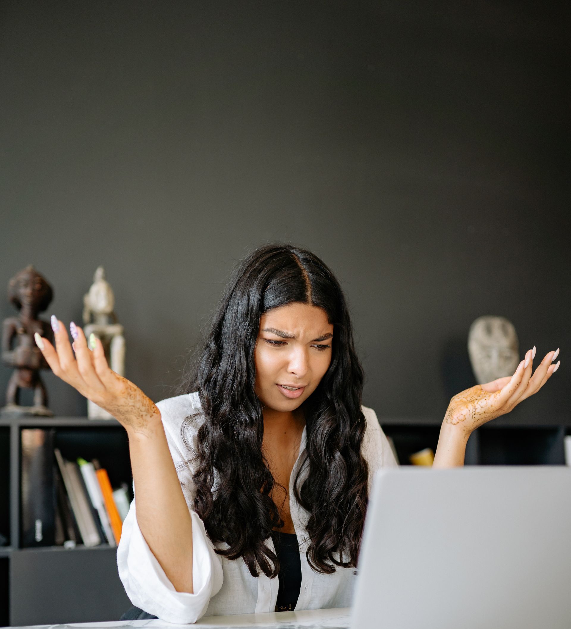 A woman is sitting at a desk looking at a laptop computer.
