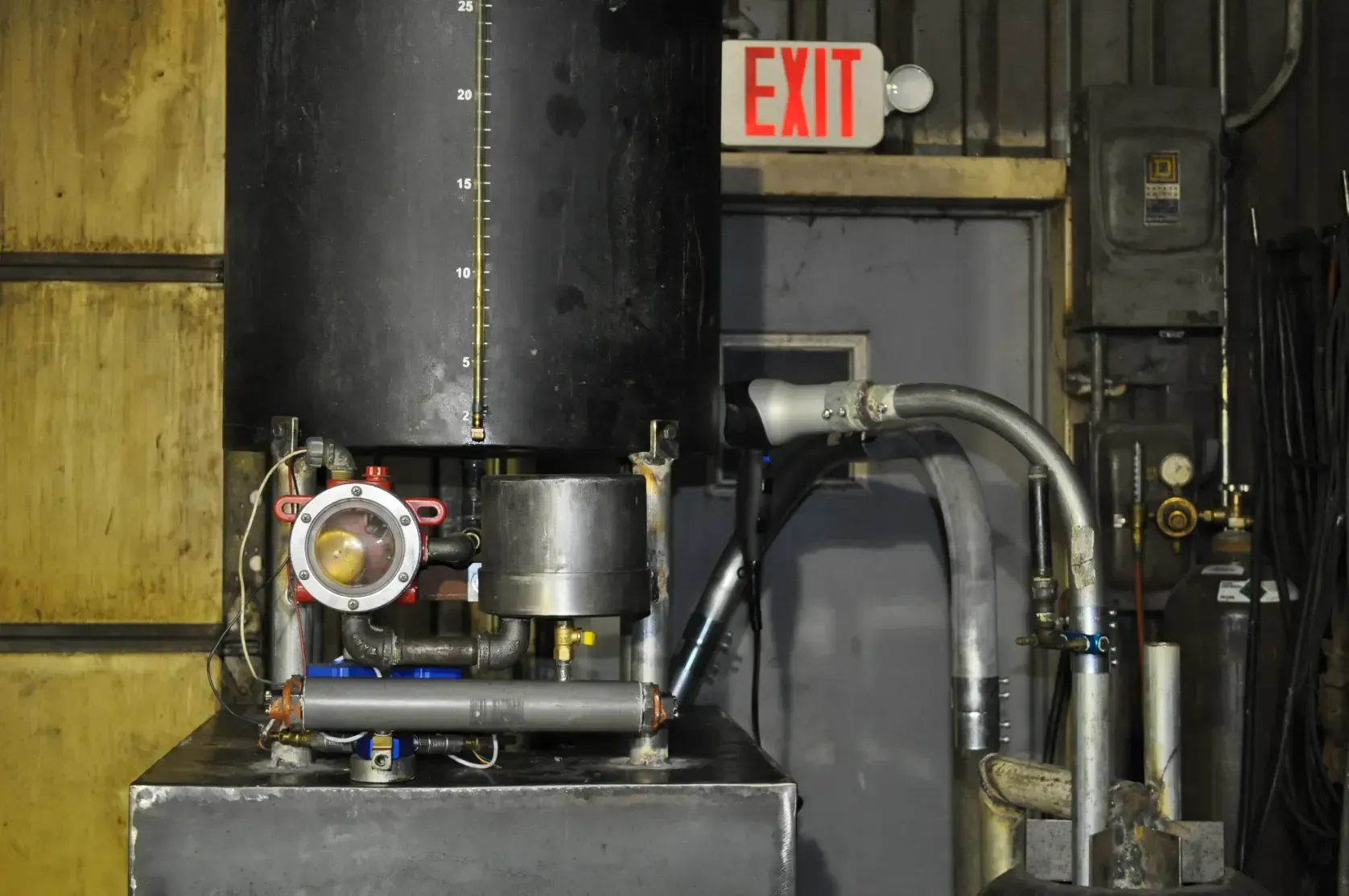 A red exit sign is above a machine in a room.