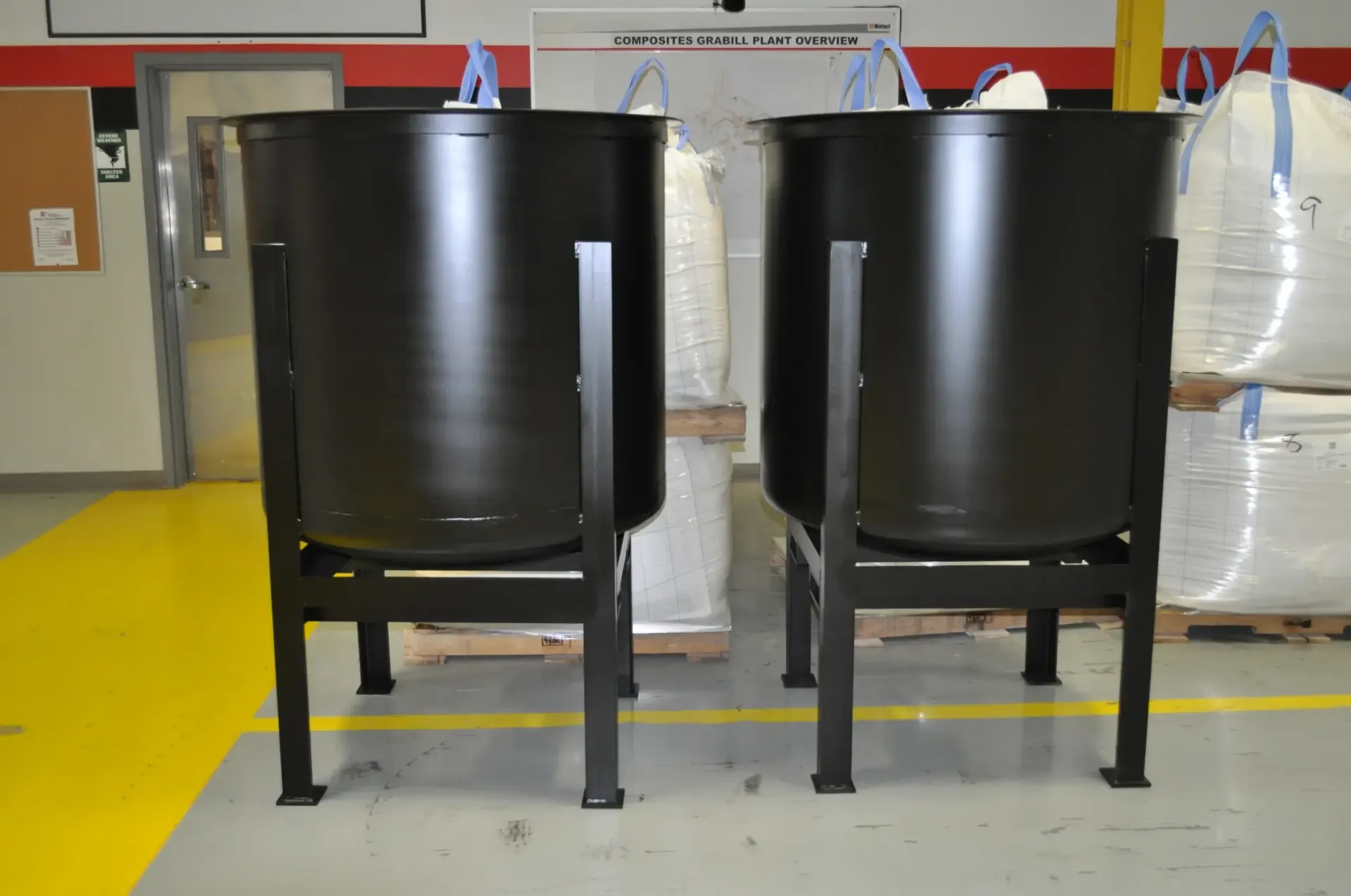 Two black tanks are sitting next to each other in a warehouse