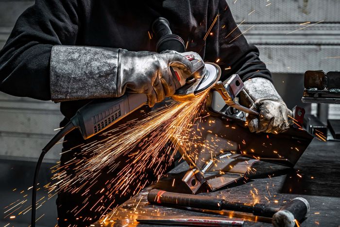 A man is grinding a piece of metal with a grinder.