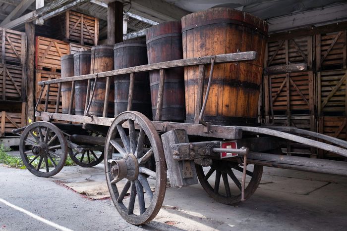 A wooden cart filled with wooden barrels in a warehouse